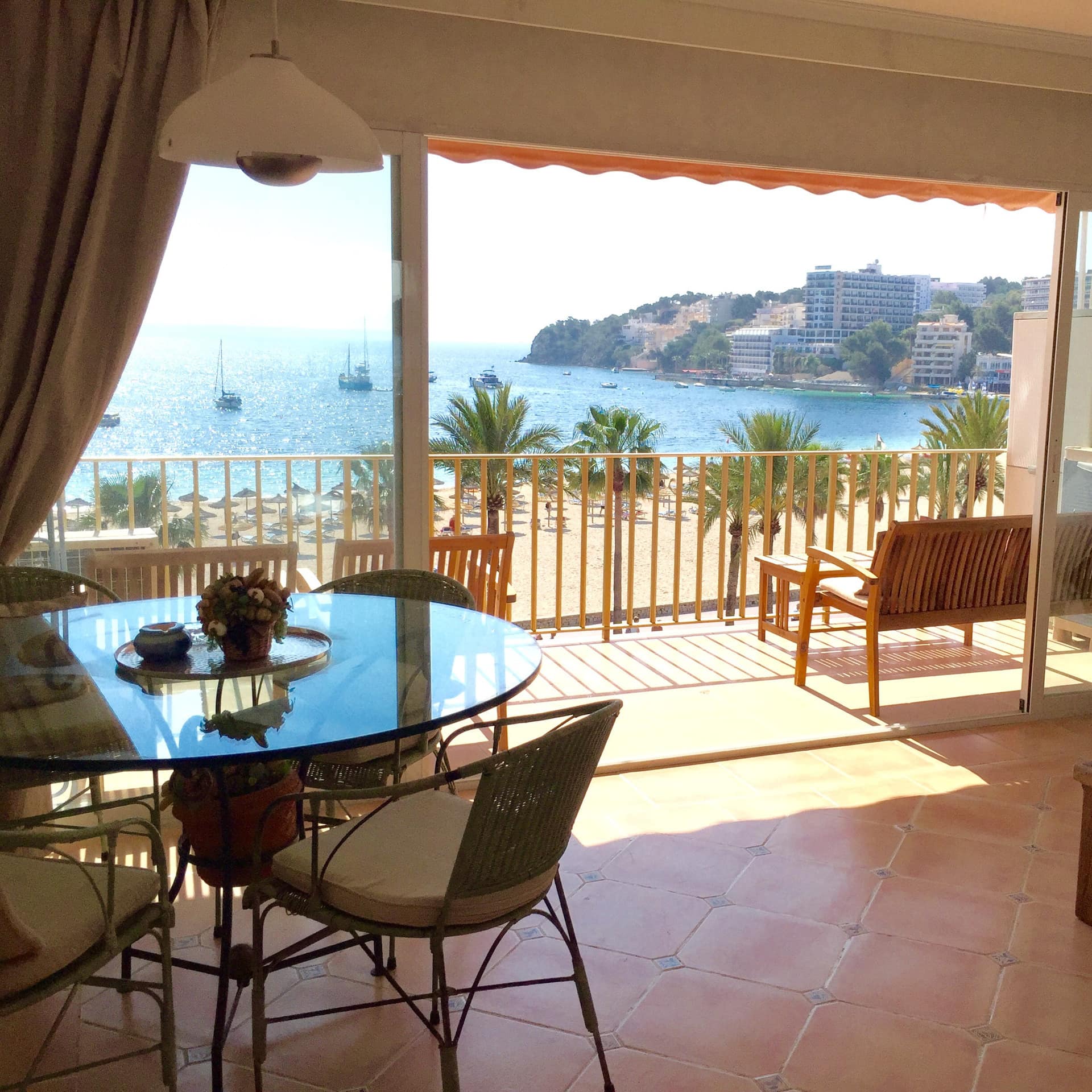 Ferienwohnung auf Mallorca mit großem Wohnraum und Balkon mit Meerblick, darauf Szühle und kleine Tische