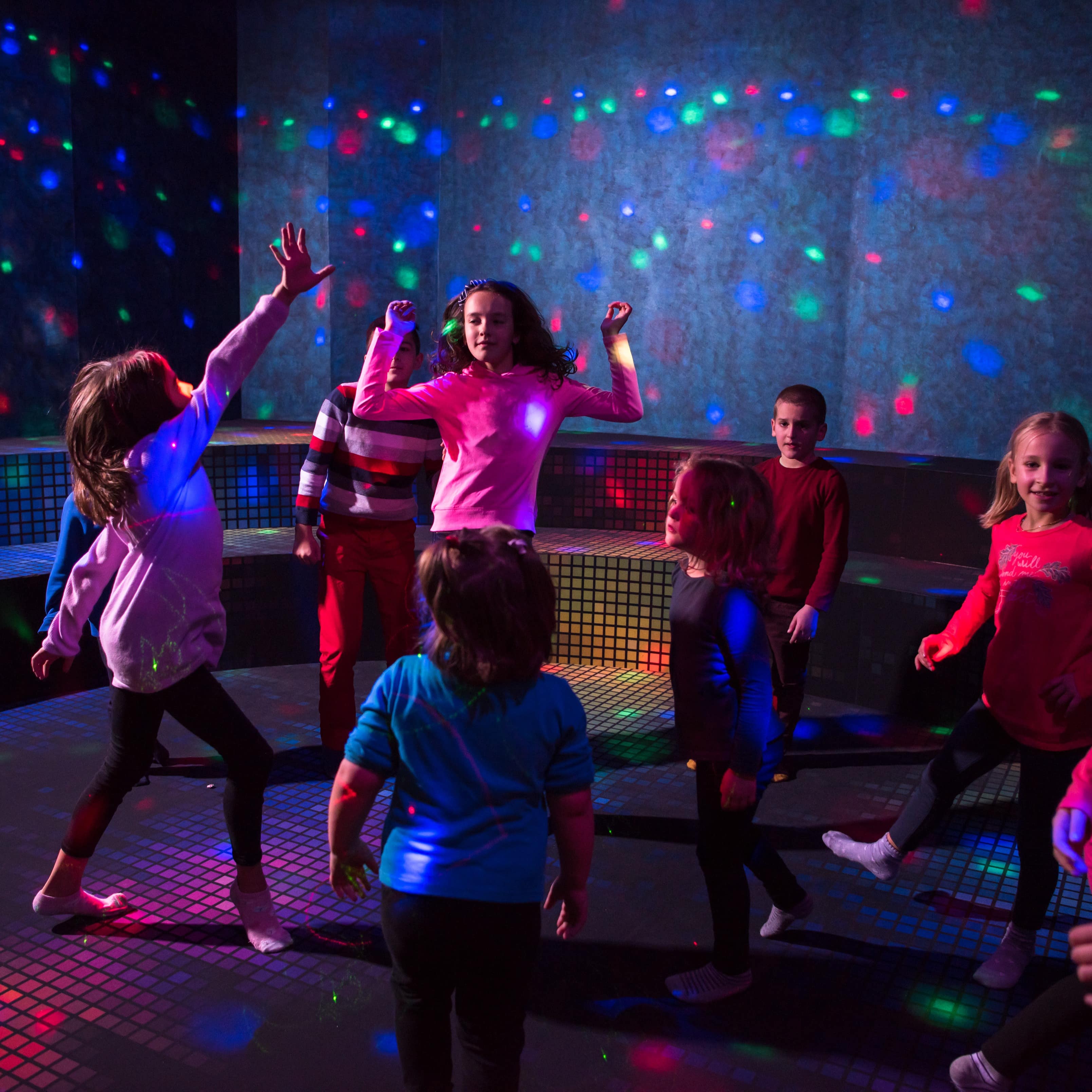 Kinder tanzen in einer bunt erleuchteten Kinderdisco.