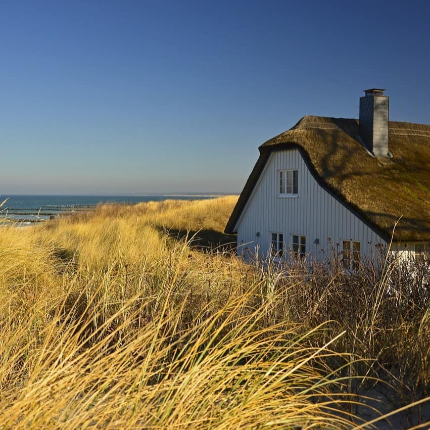 Ein Haus mit Reetdach in den Dünen direkt am Meer.