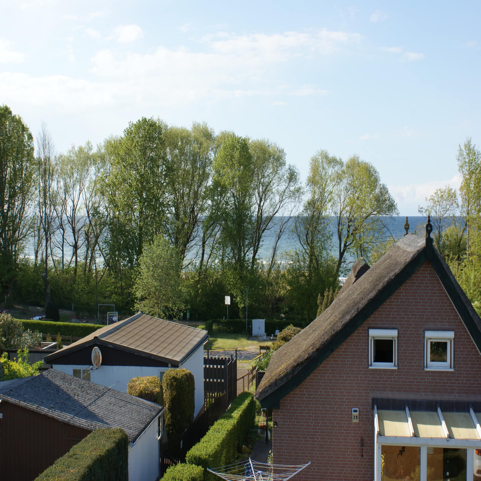 Blick aus einem Fenster über andere Häuser auf das Meer. 