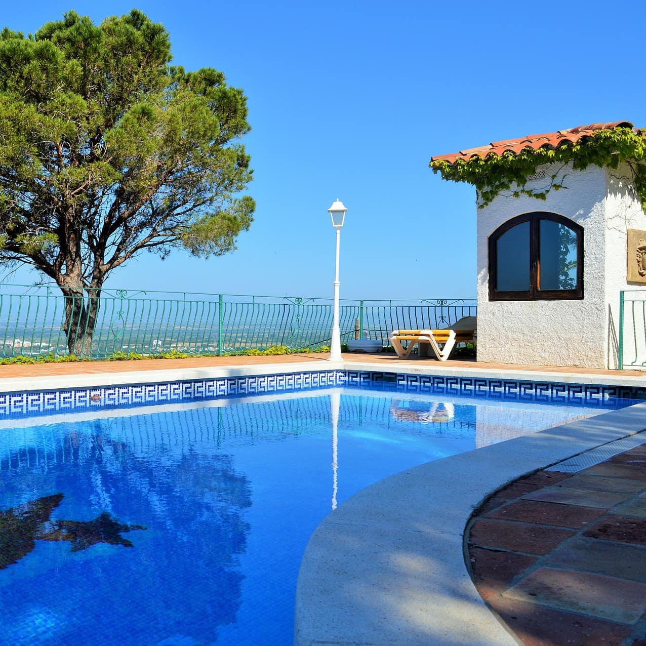 Blick über einen Pool im Garten auf das weiter unten liegende Umland