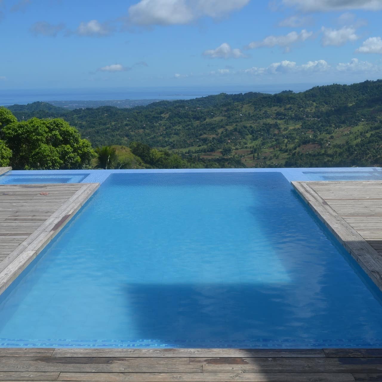 Infinity-Pool mit Holzdeck und Blick auf das bewaldete Umland