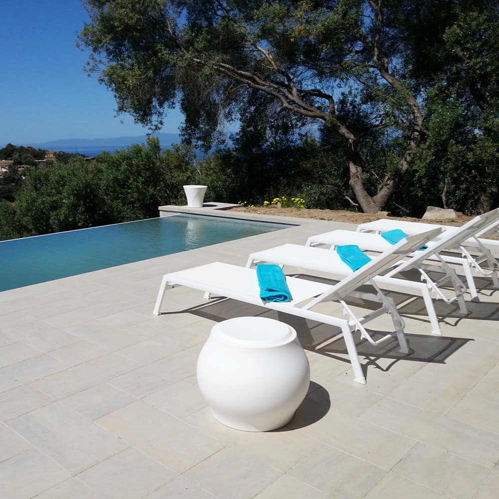 Terrasse mit Sonnenliegen eines Ferienhauses auf Sardinien am Meer mit einem Infinity Pool