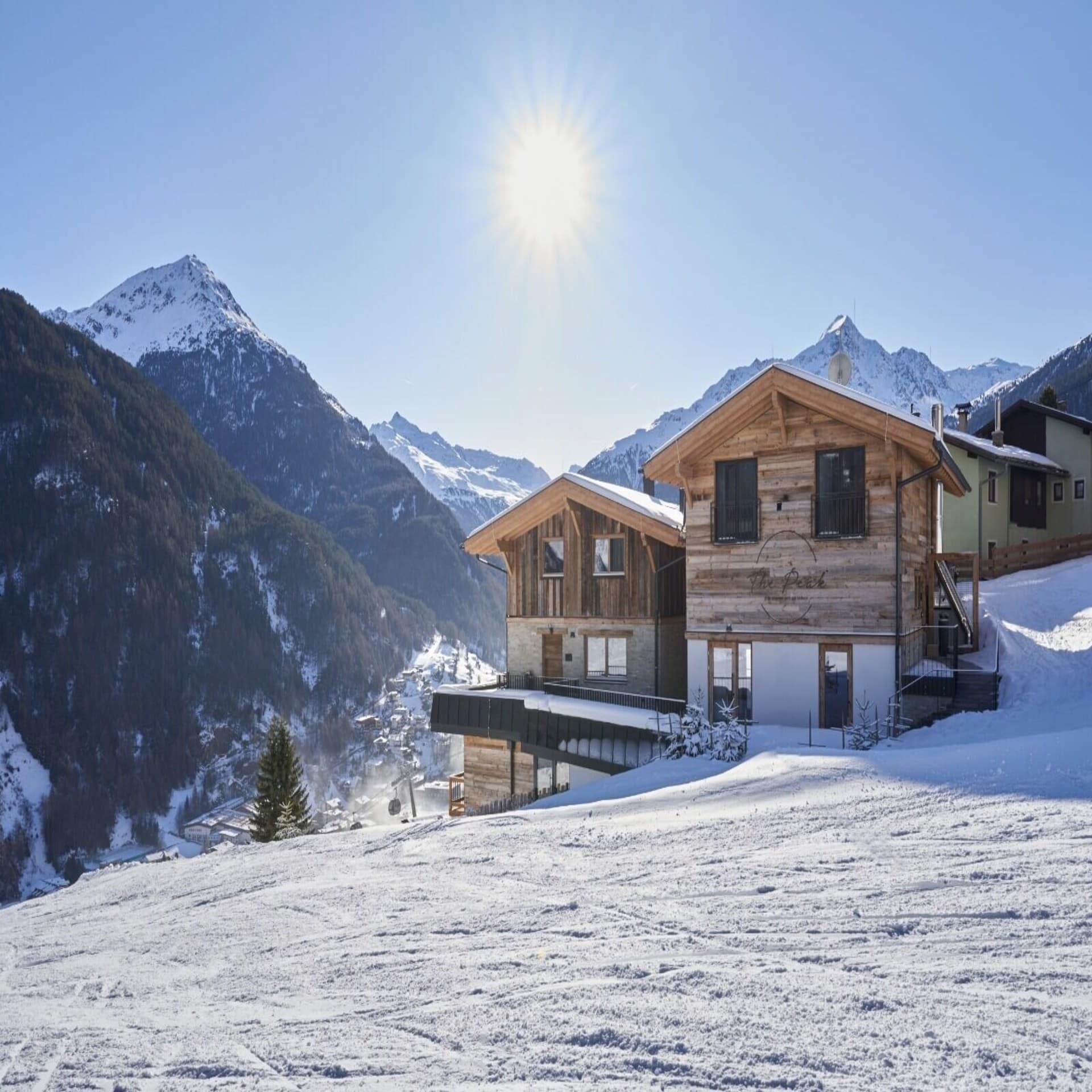 Urige Holzhütten an einer Skipiste in Tirol. Die Sonne scheint, es liegt Schnee. 