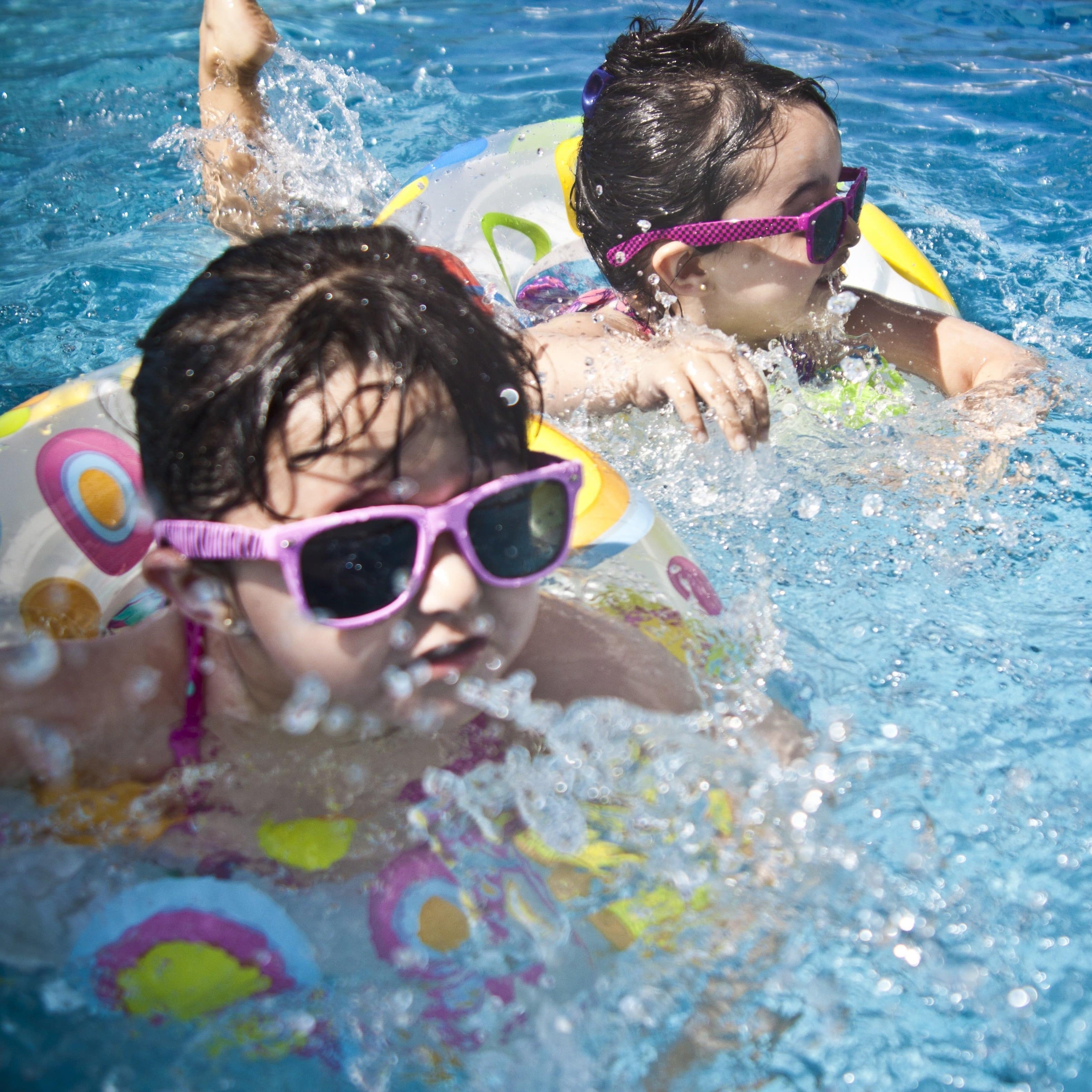 Zwei Mädchen mit Wasserreifen in einem Schwimmbad.