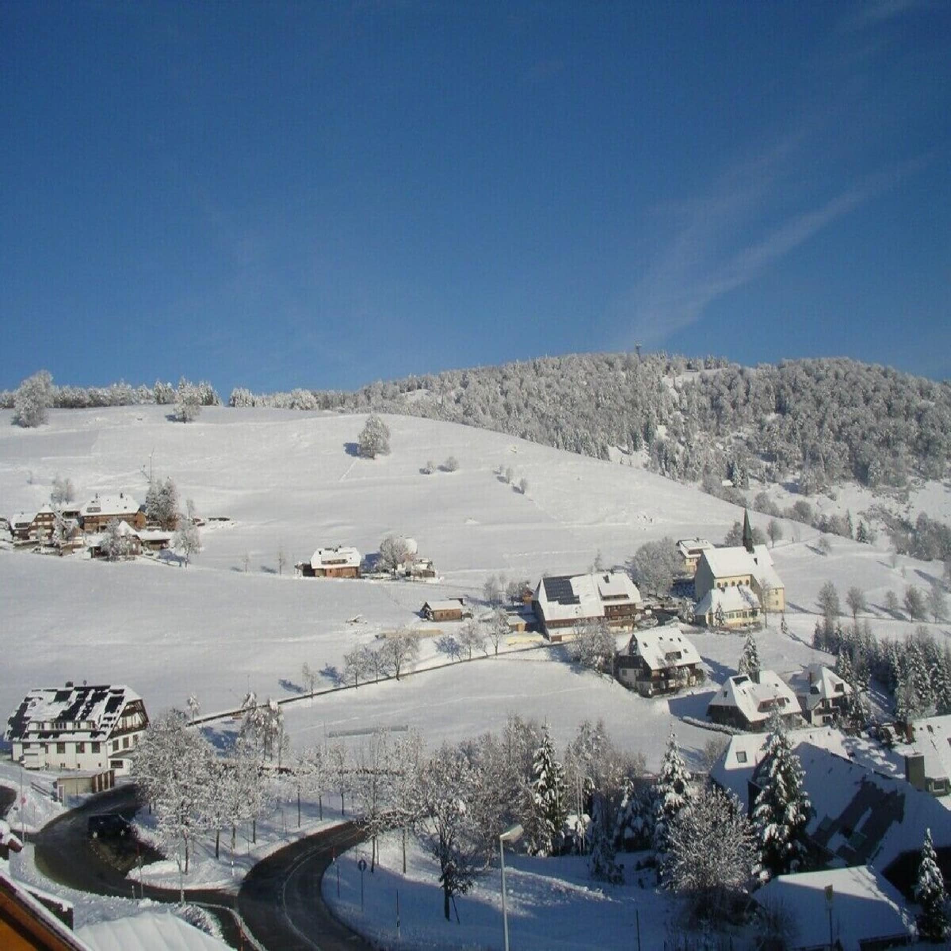 Blick von einem Haus auf die verschneite ländliche Umgebung. Die Sonne scheint.