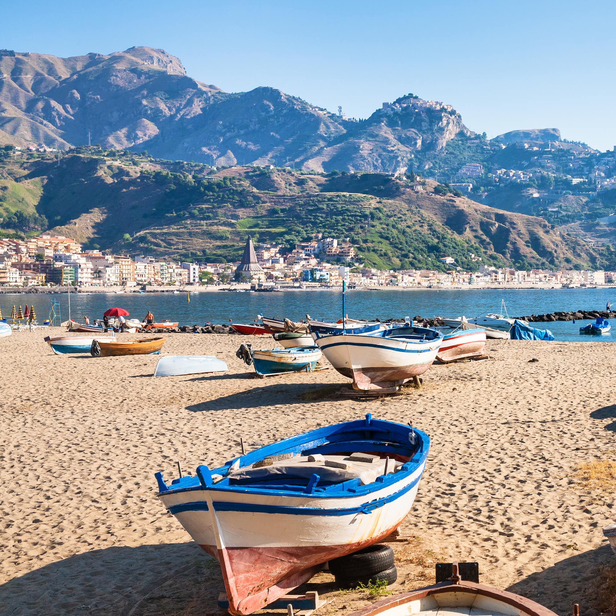 Lauter Ruderboote am Strand von Naxos, dahinter Stadt und Berge.