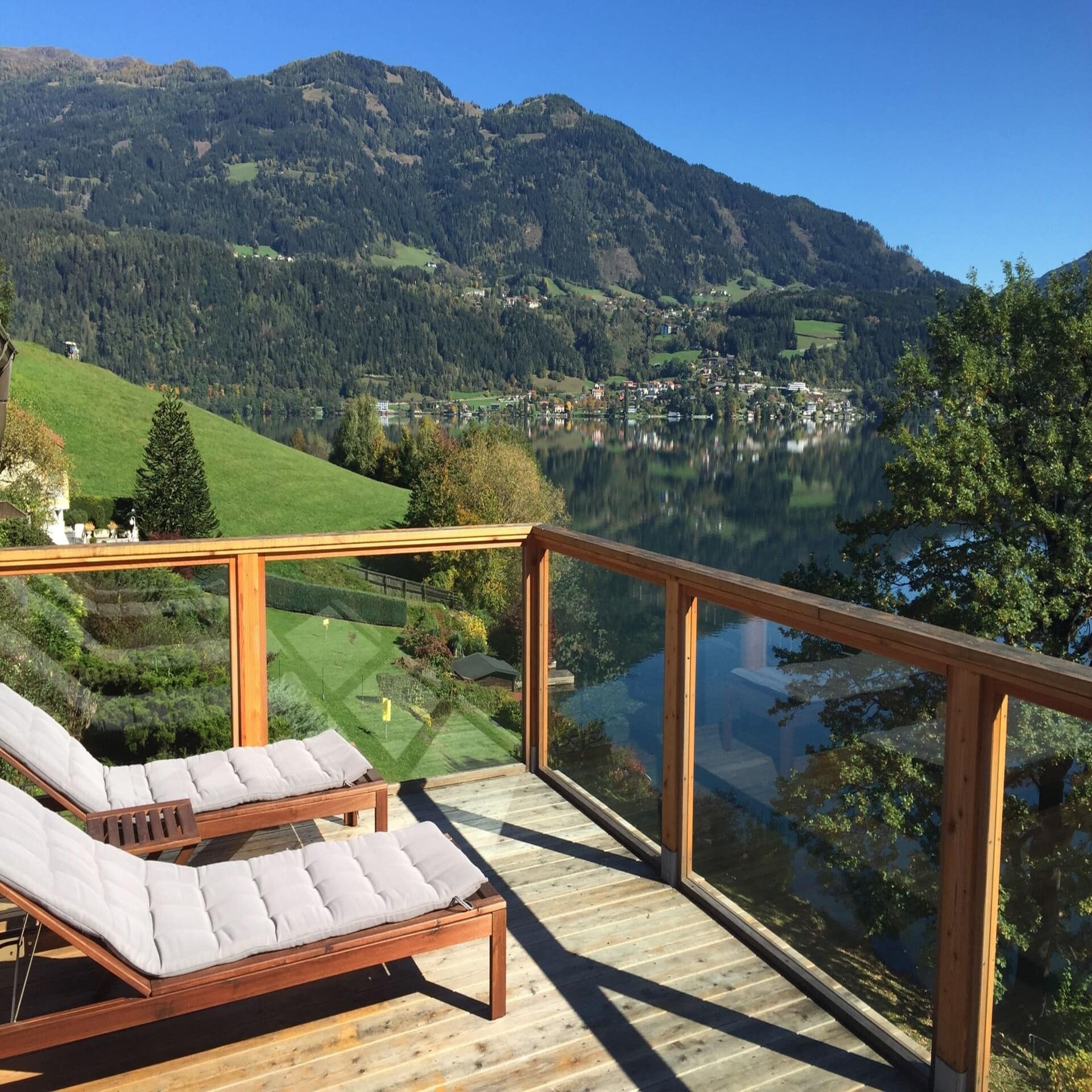 Sonniger Balkon mit Liegestühlen und Aussicht auf einen See in Österreich. 