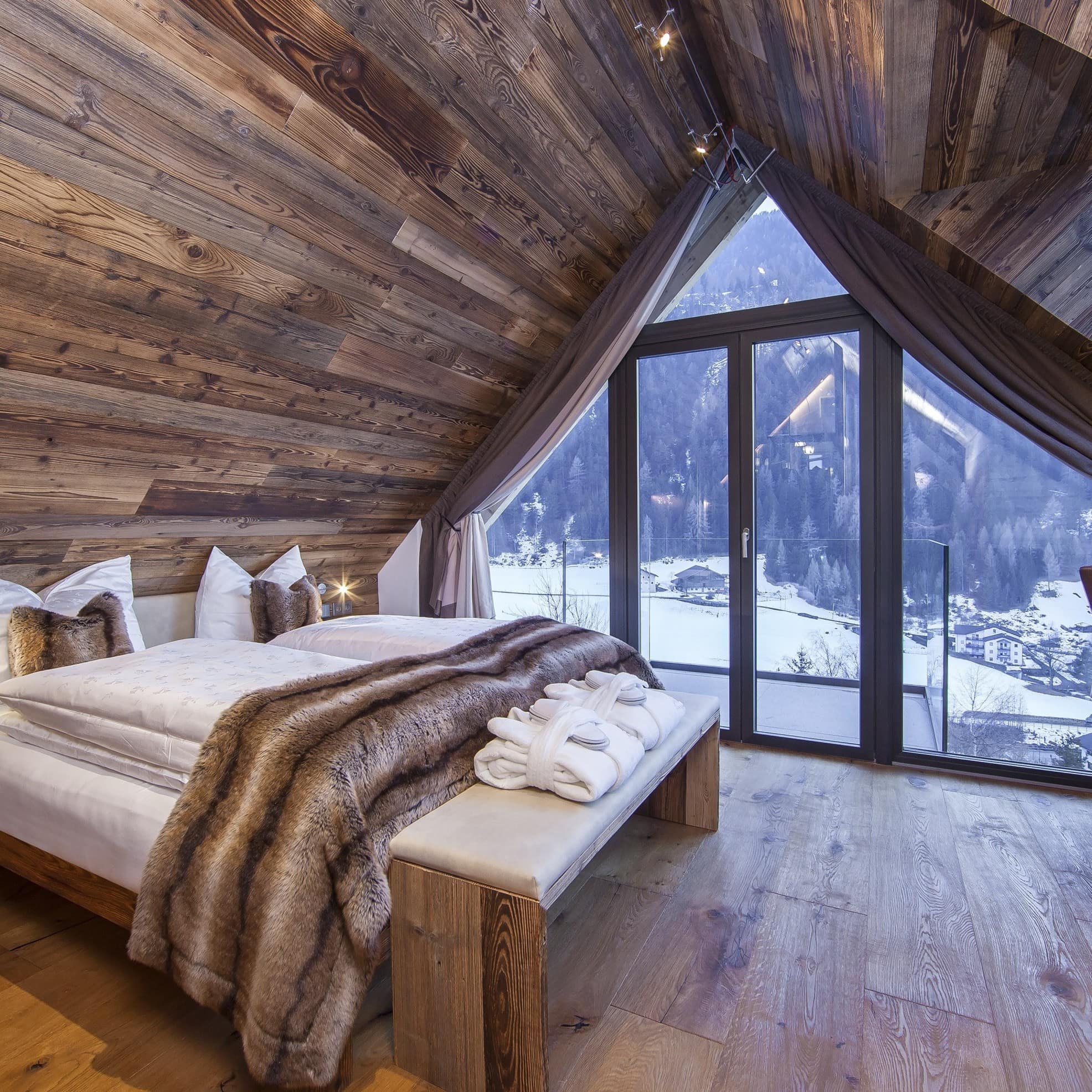 Schlafzimmer eines Luxus-Chalets mit Panoramafenster in St. Ulrich in Gröden