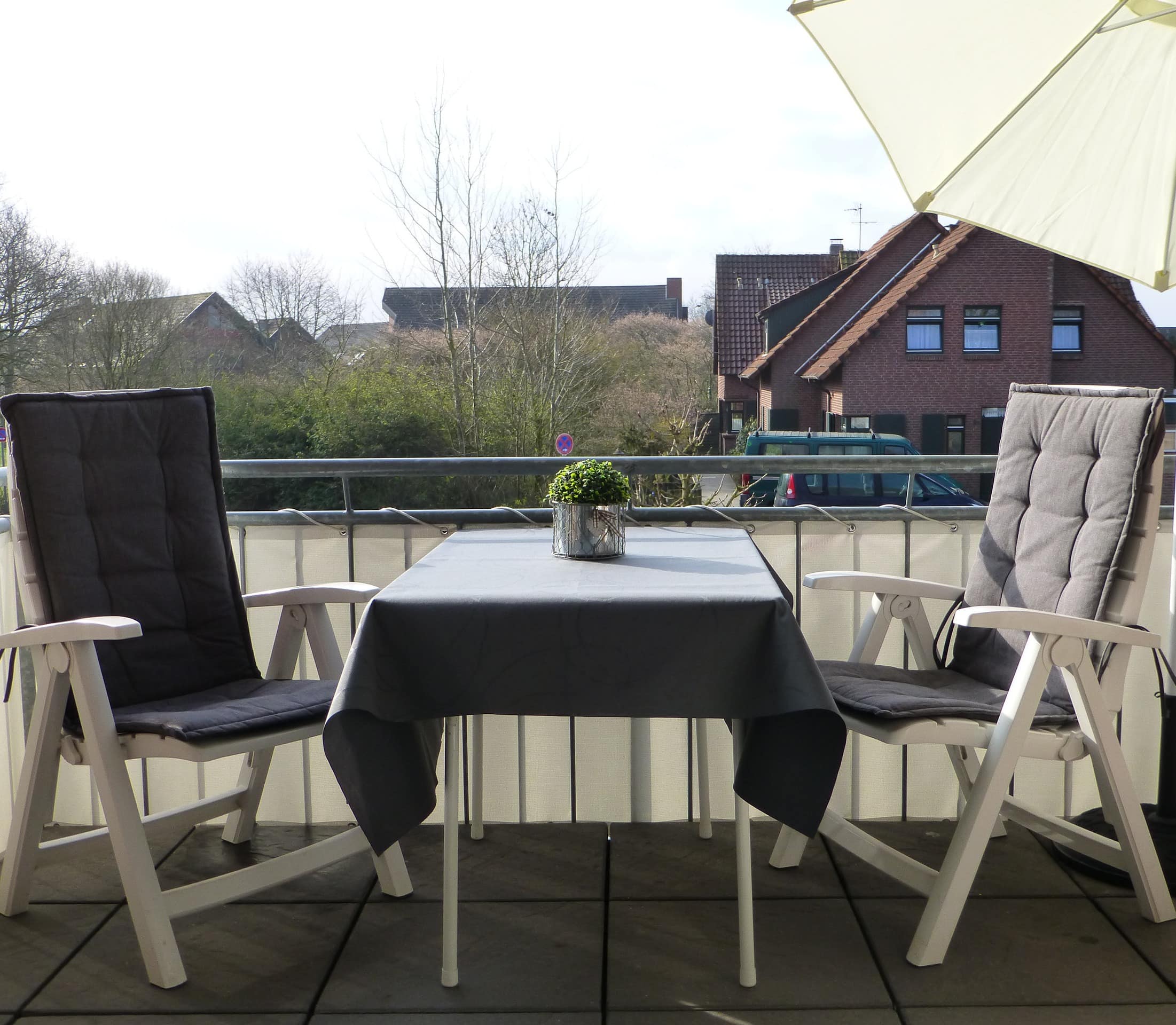 Balkon mit Tisch, zwei Stühlen und Sonnenschirm in einer Ferienwohnung in Dangast