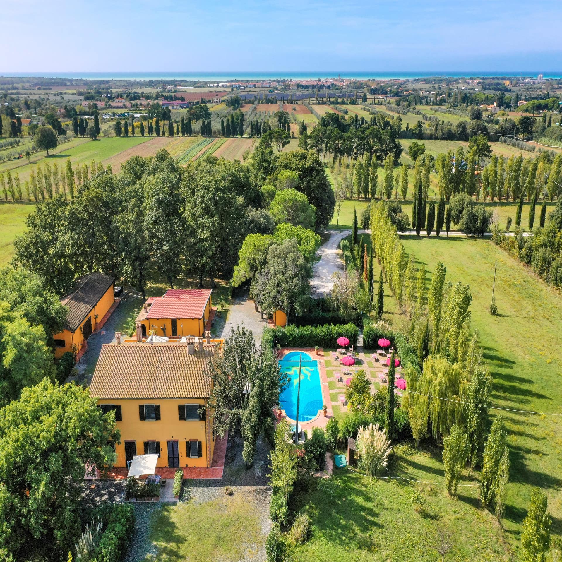 Livorno: Blick von oben auf ein Haus mit Garten und Pool und Blick auf die Landschaft, in der Ferne das Meer.