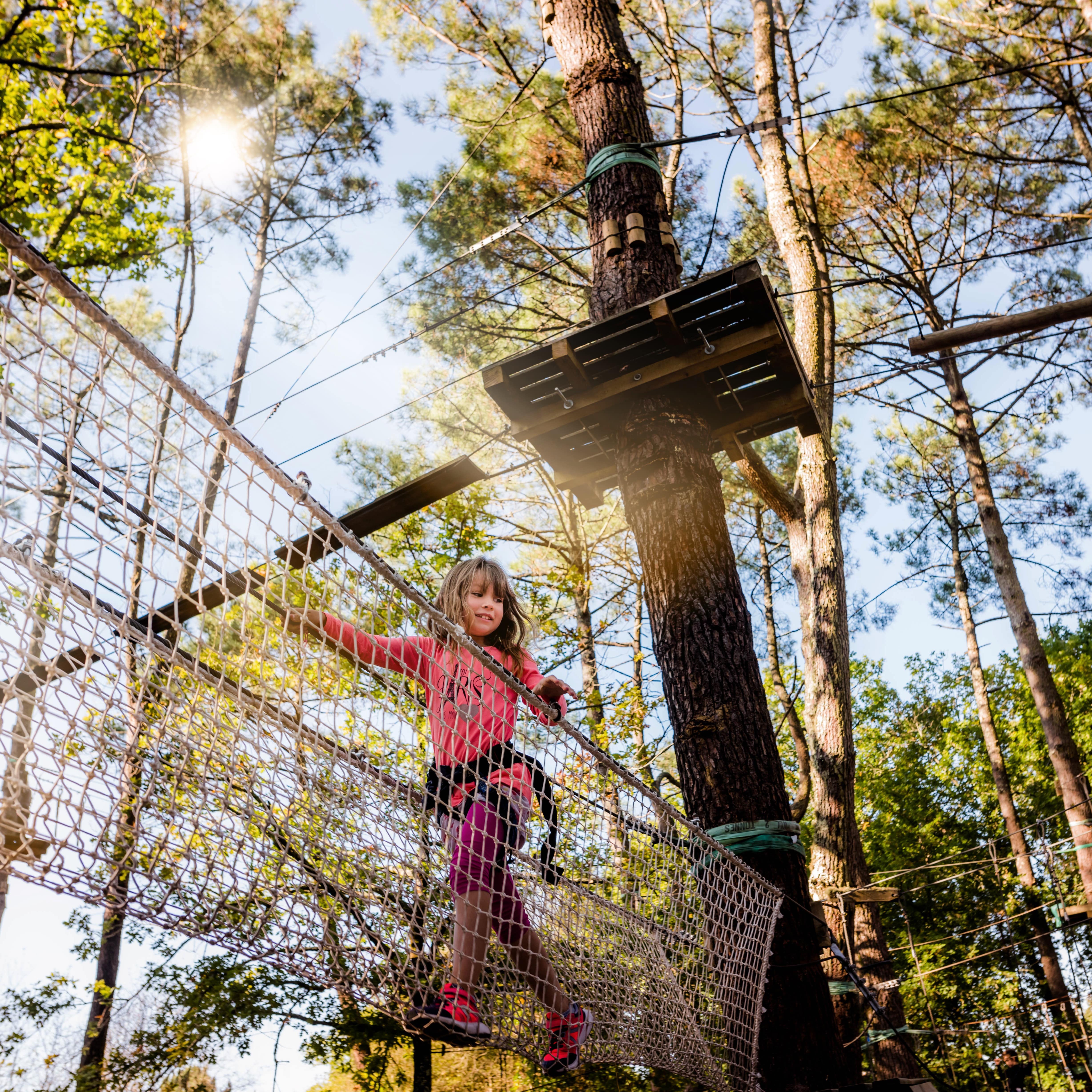 Ein Mädchen balanciert in einem Netz in einem Kletterpark.