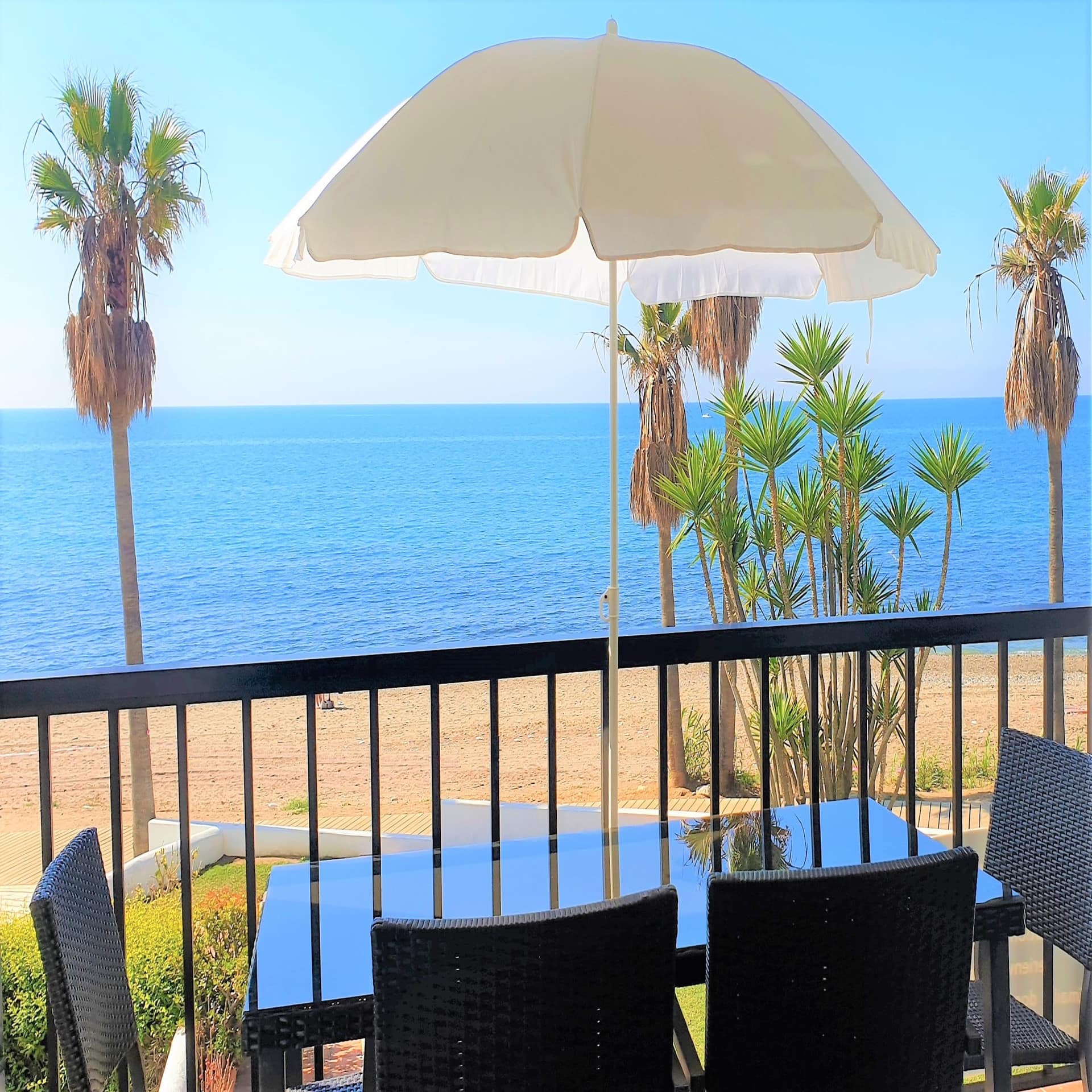 Tisch mit Sonnenschirm auf einem Balkon direkt gegenüber vom Strand in Andalusien.
