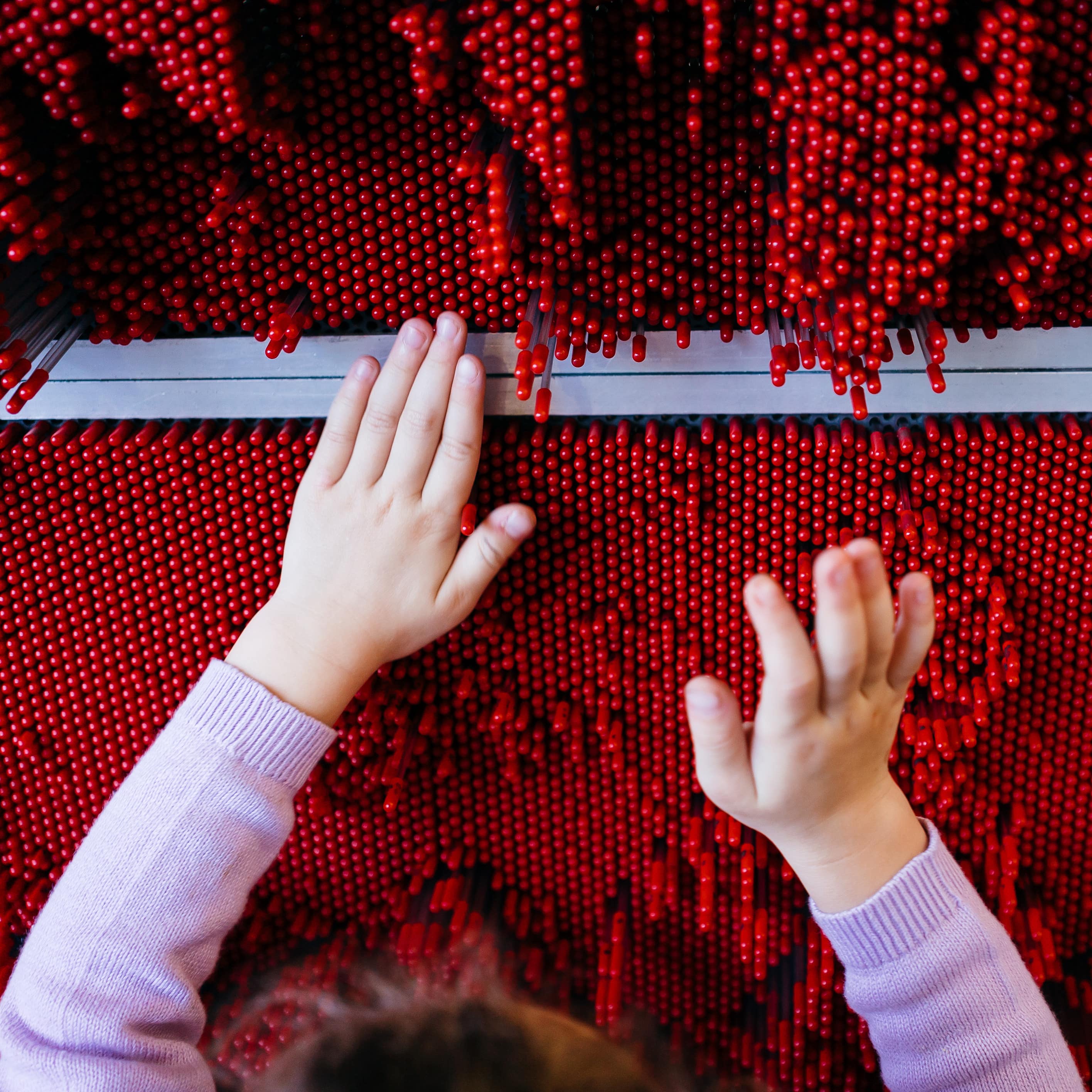 Kind spielt mit einem roten Ausstellungsstück in einem Naturkundemuseum.