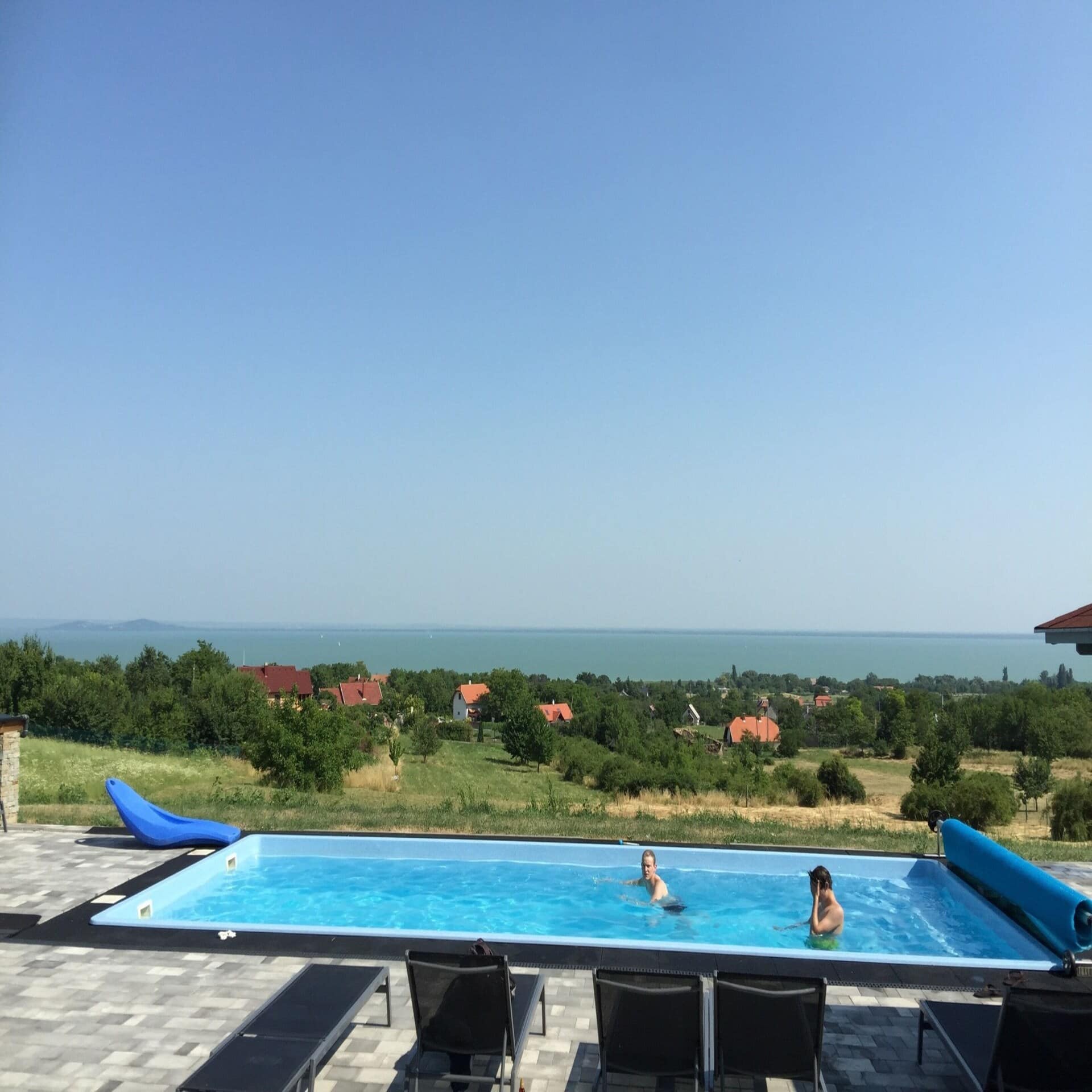 2 Personen schwimmen in einem Pool mit Blick auf die Landschaft und den Plattensee.