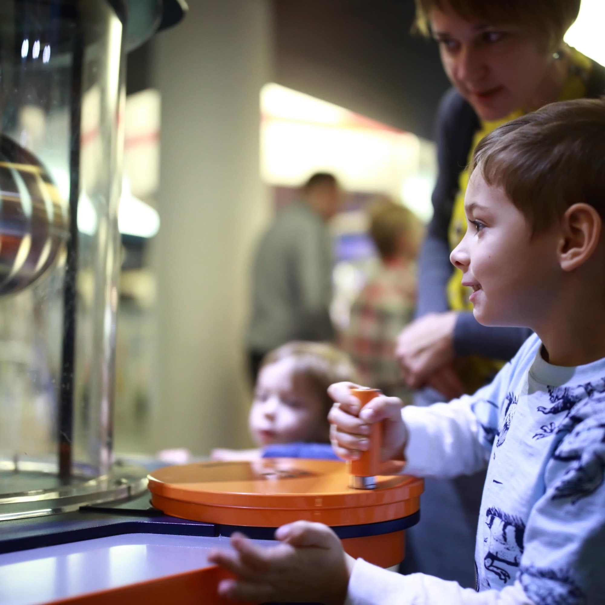 Im Kindermuseum: Ein Junge dreht an einer Kurbel und beobachtet was passiert.