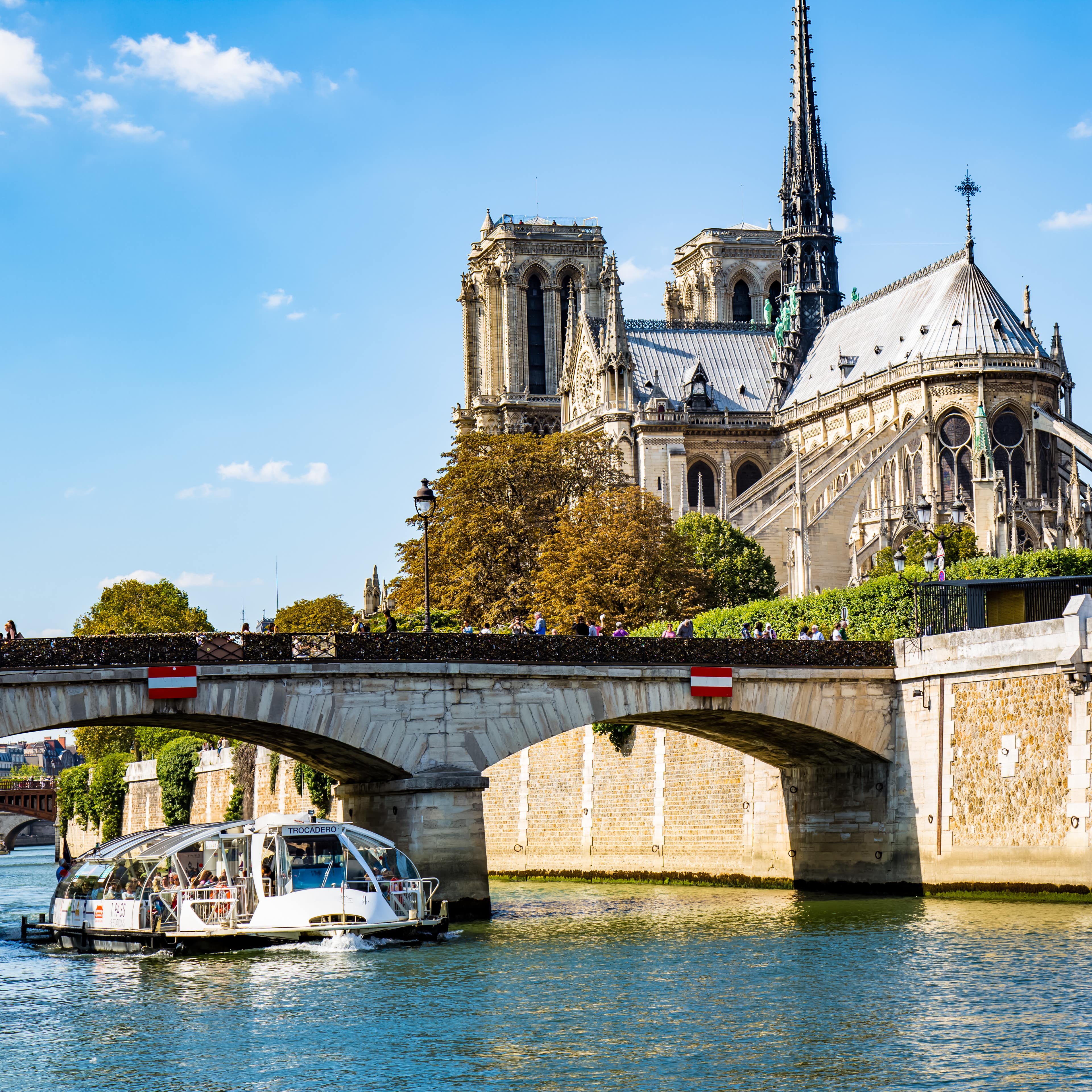 Ein Batobus fährt unter einer Brücke an Notre Dame vorbei.