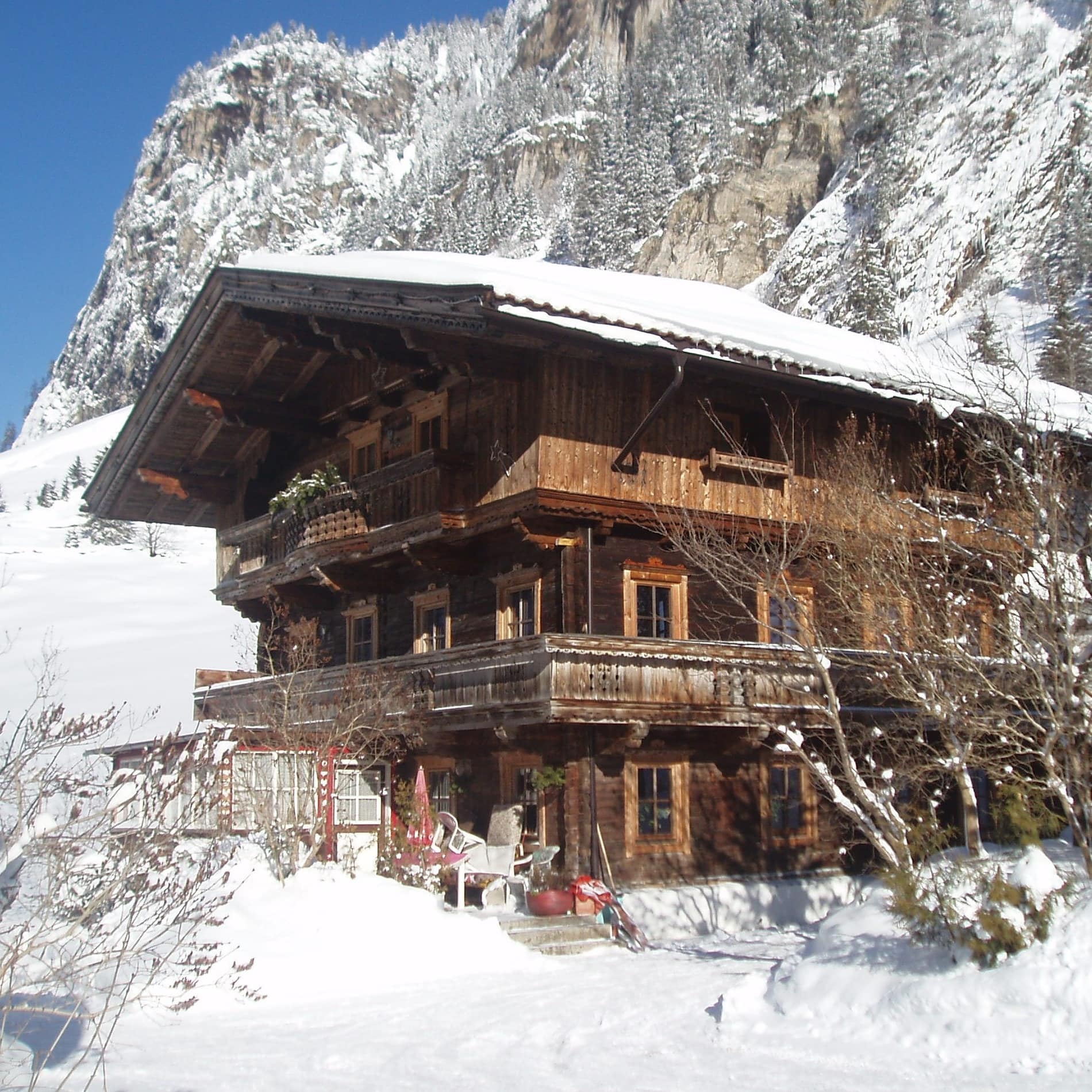 Traditionelles Tiroler Holzhaus mit umlaufendem Balkon in Schneelandschaft