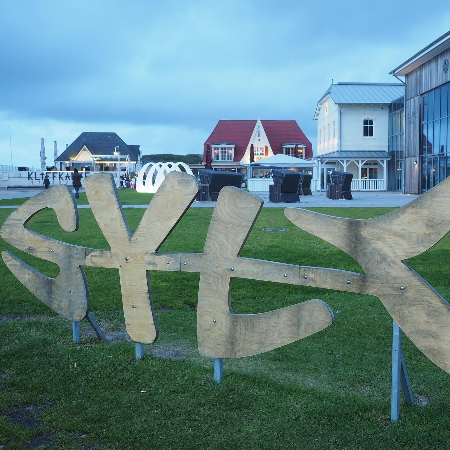 Ein Sylt-Schriftzug in Fischform und Häuser im Hintergrund in Wenningstedt