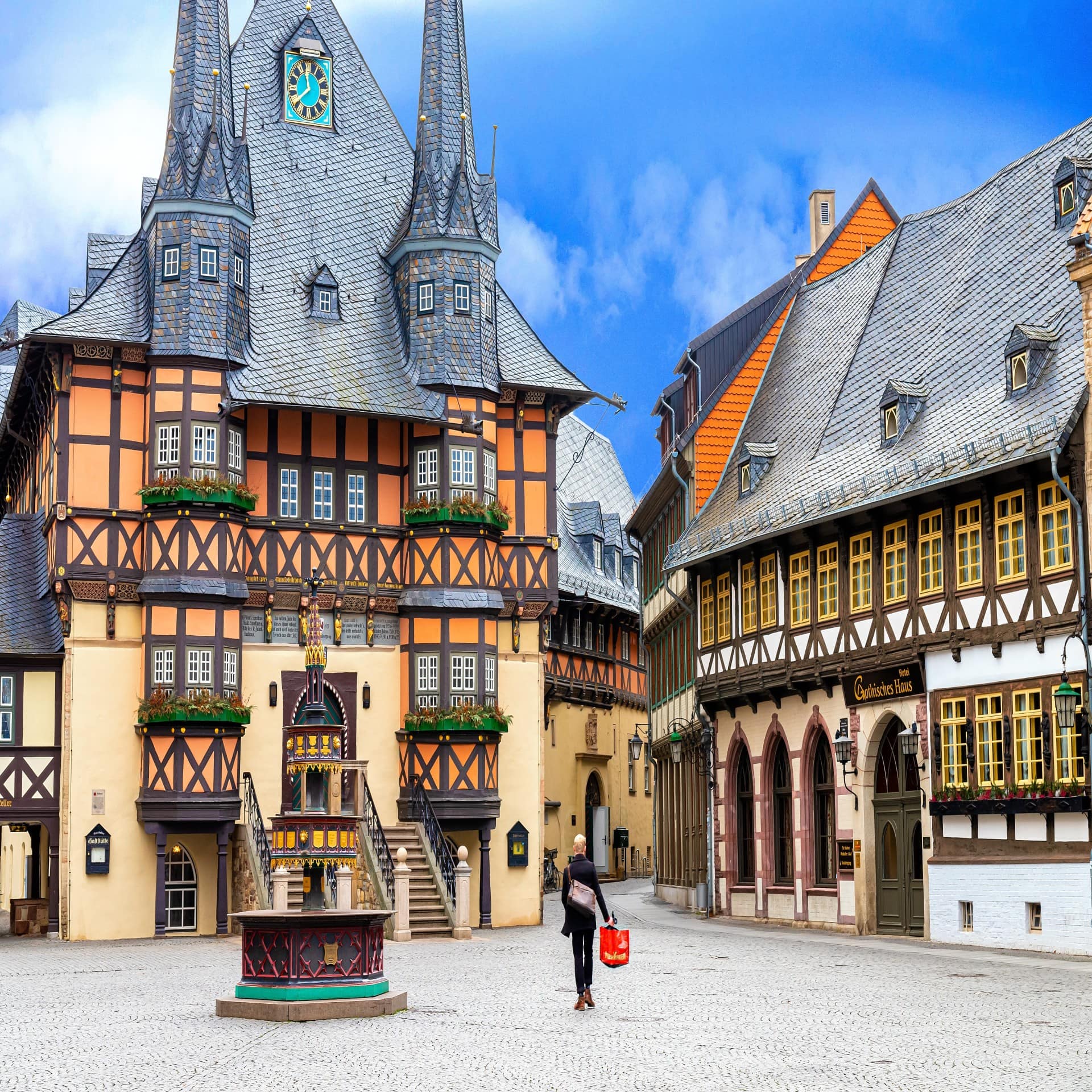 Ein Mann mit roter Tüte läuft über einen Platz in der Altstadt von Wernigerode.
