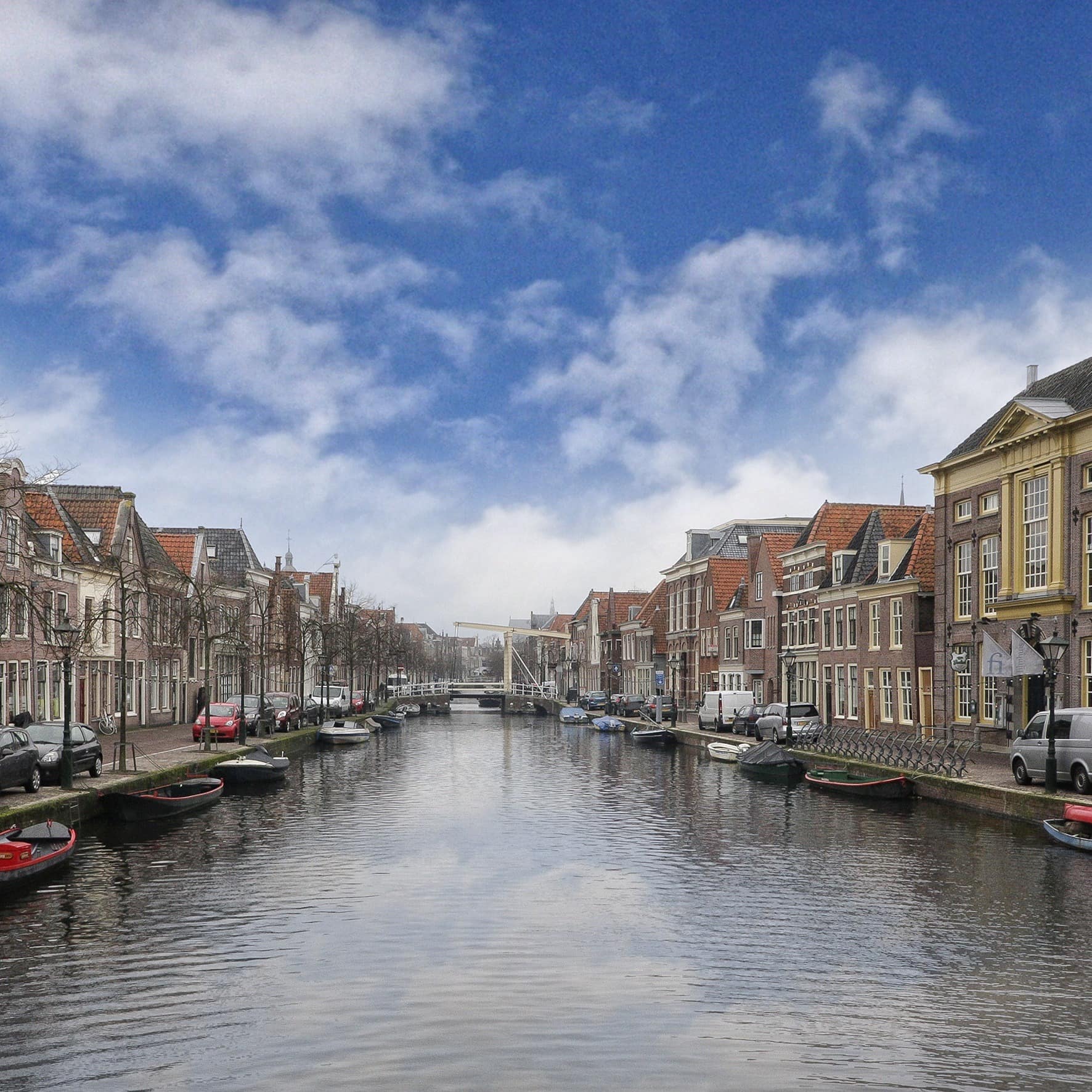 Blick eine Gracht entlang in der kleine Boote ankern, links und rechts stehen Häuser