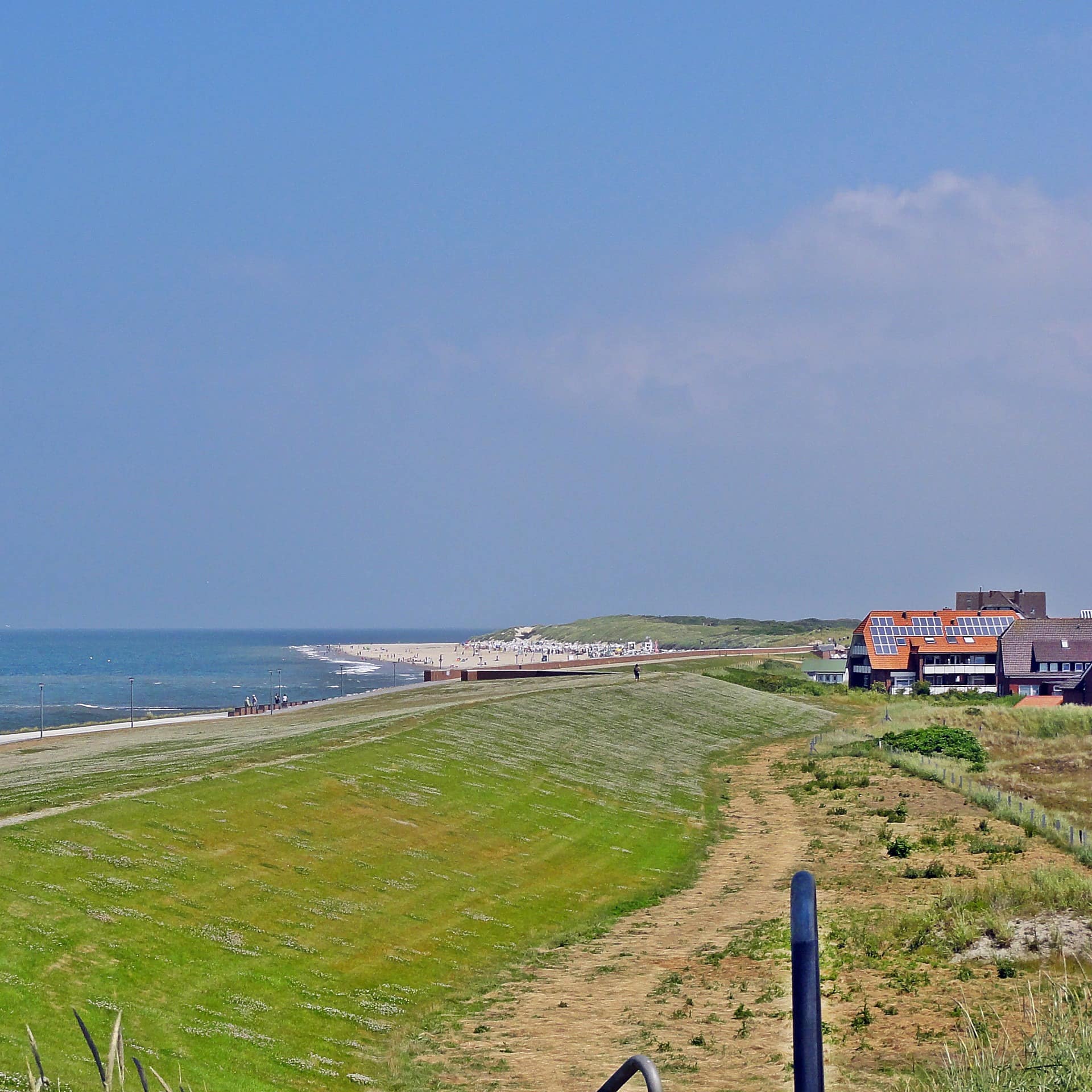 Blick am Deich von Baltrum entlang, links das Meer, rechts Häuser mit Ferienwohnungen