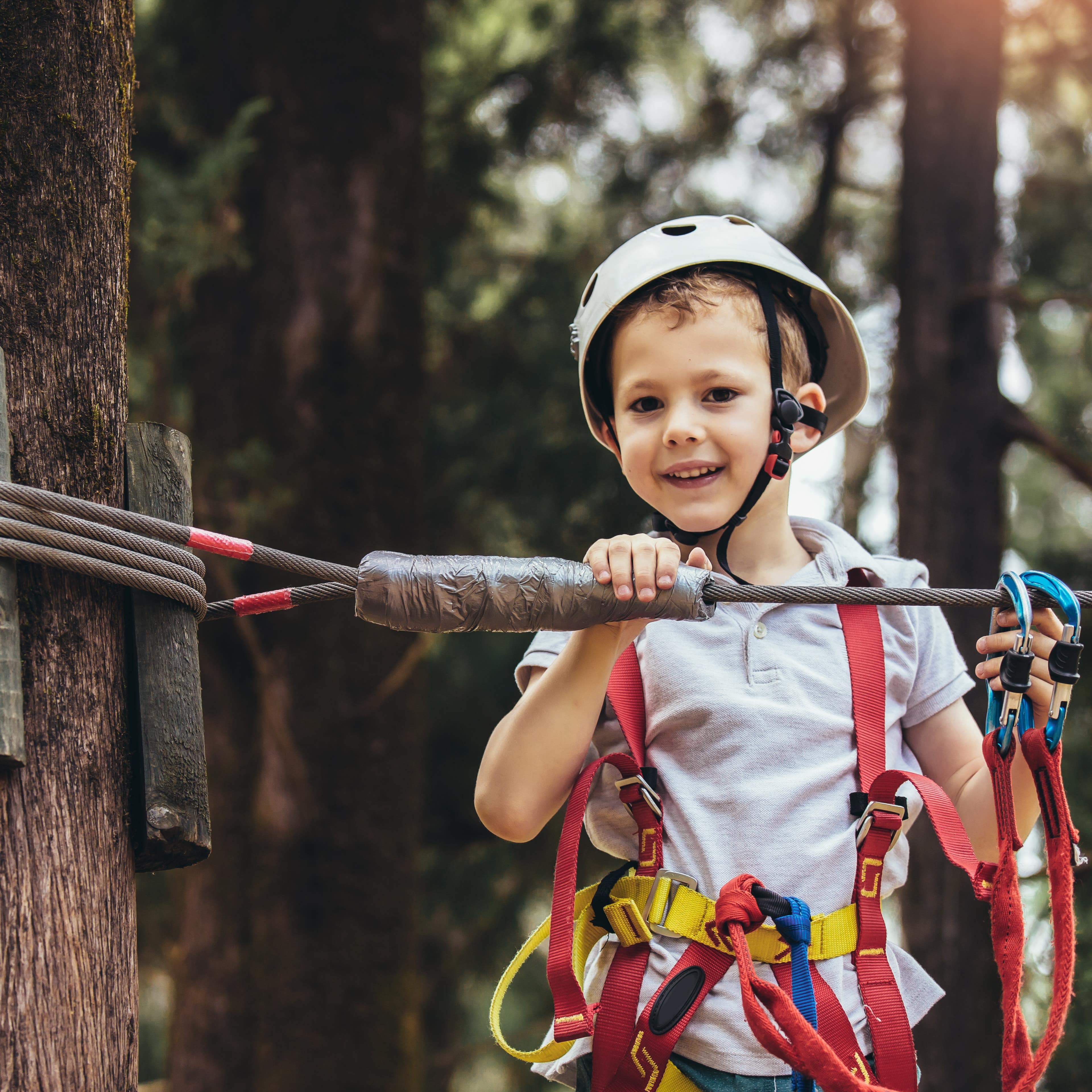 Ein Junge mit Kletterausrüstung in einem Kletterwald