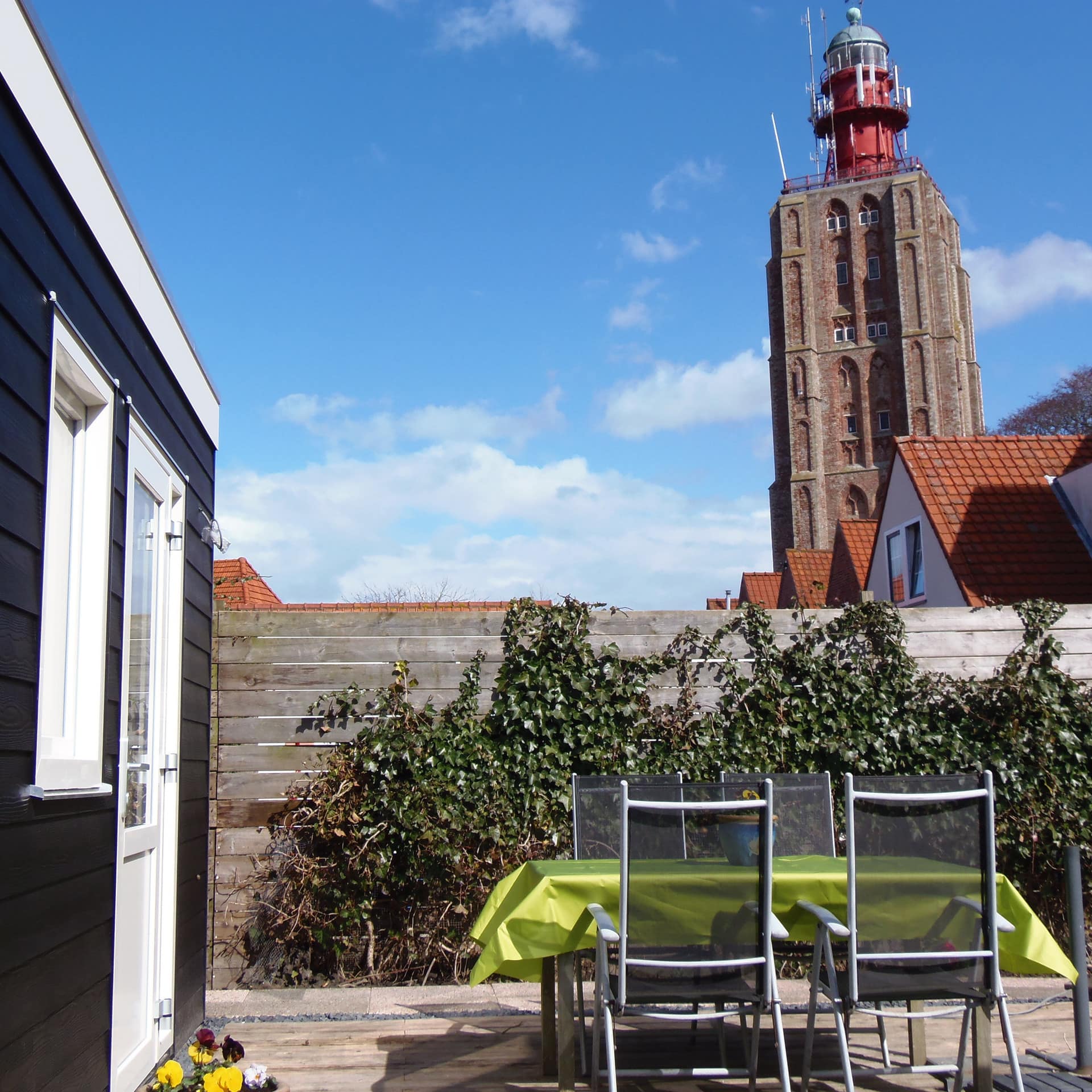 Ferienwohnung in Westkapelle mit Terrasse mit Tisch und Stühlen und Blick auf den Leuchtturm in einem ehemaligen Kirchturm