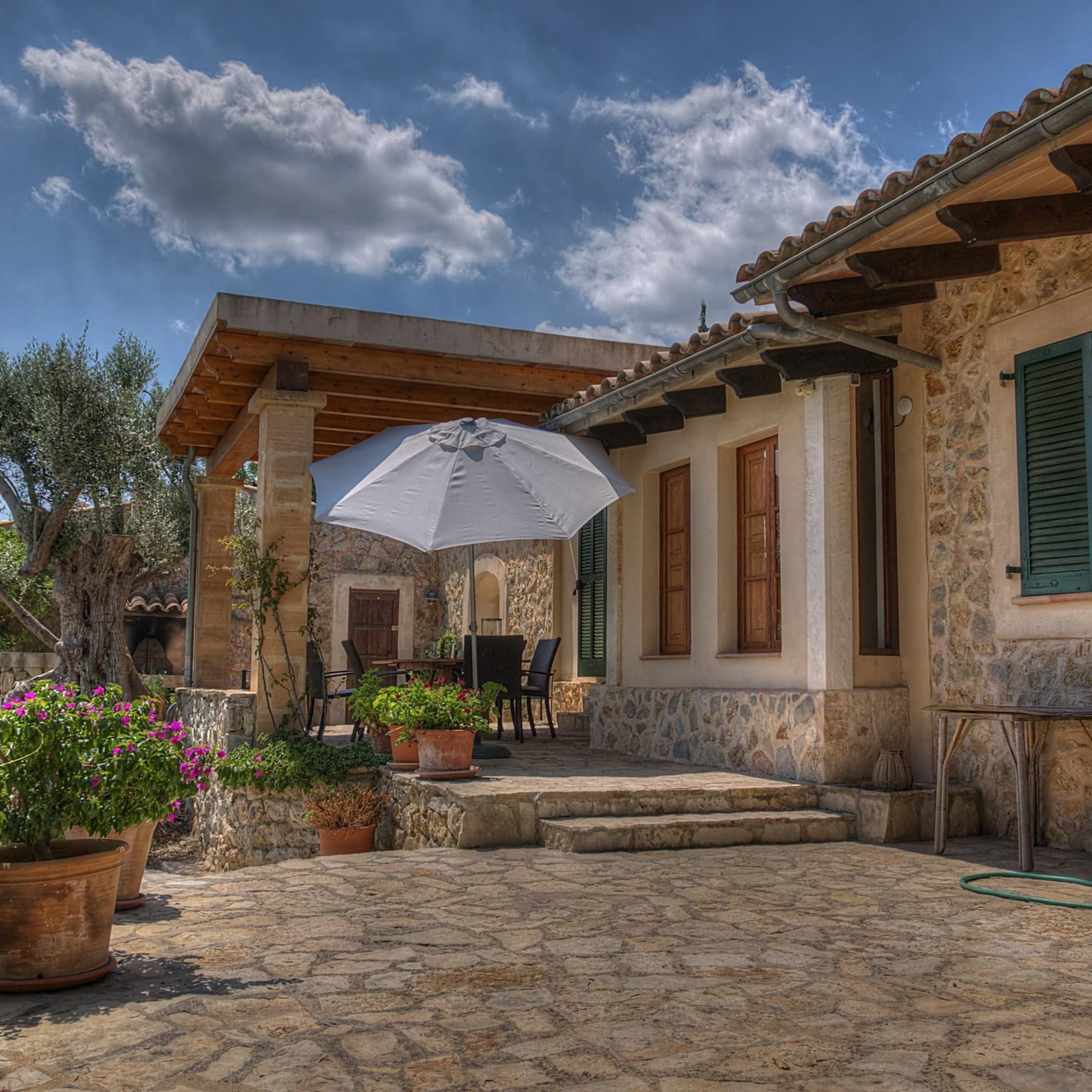 Seitenblick auf eine Finca mit überdachter Veranda und Garten