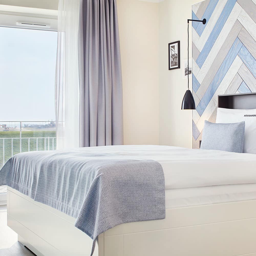 Schlafzimmer einer Traum-Ferienwohnung in Büsum mit Blick auf den Balkon mit Meerblick