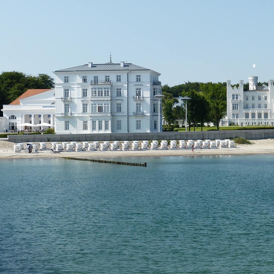 Blick auf weiße Häuser am Strand von Heiligendamm, am Strand stehen Strandkörbe. 