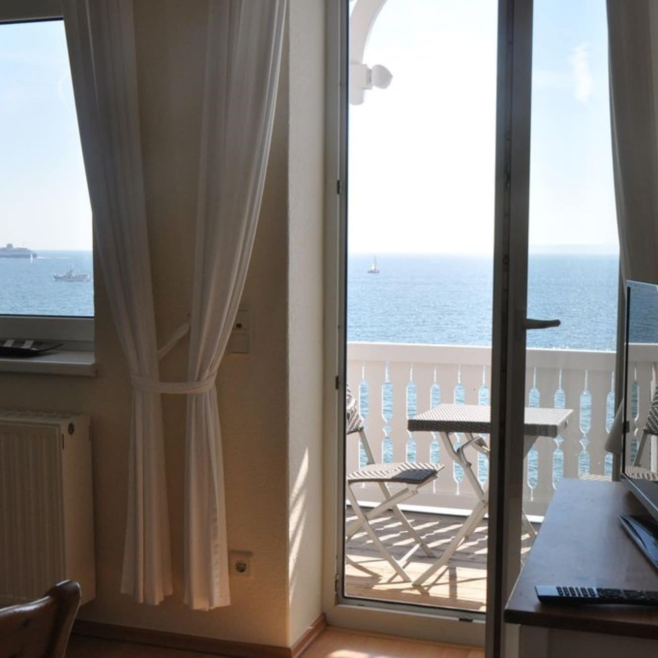 Wohnzimmer mit offener Balkontür und Meerblick in einer Ferienwohnung auf Rügen am Strand