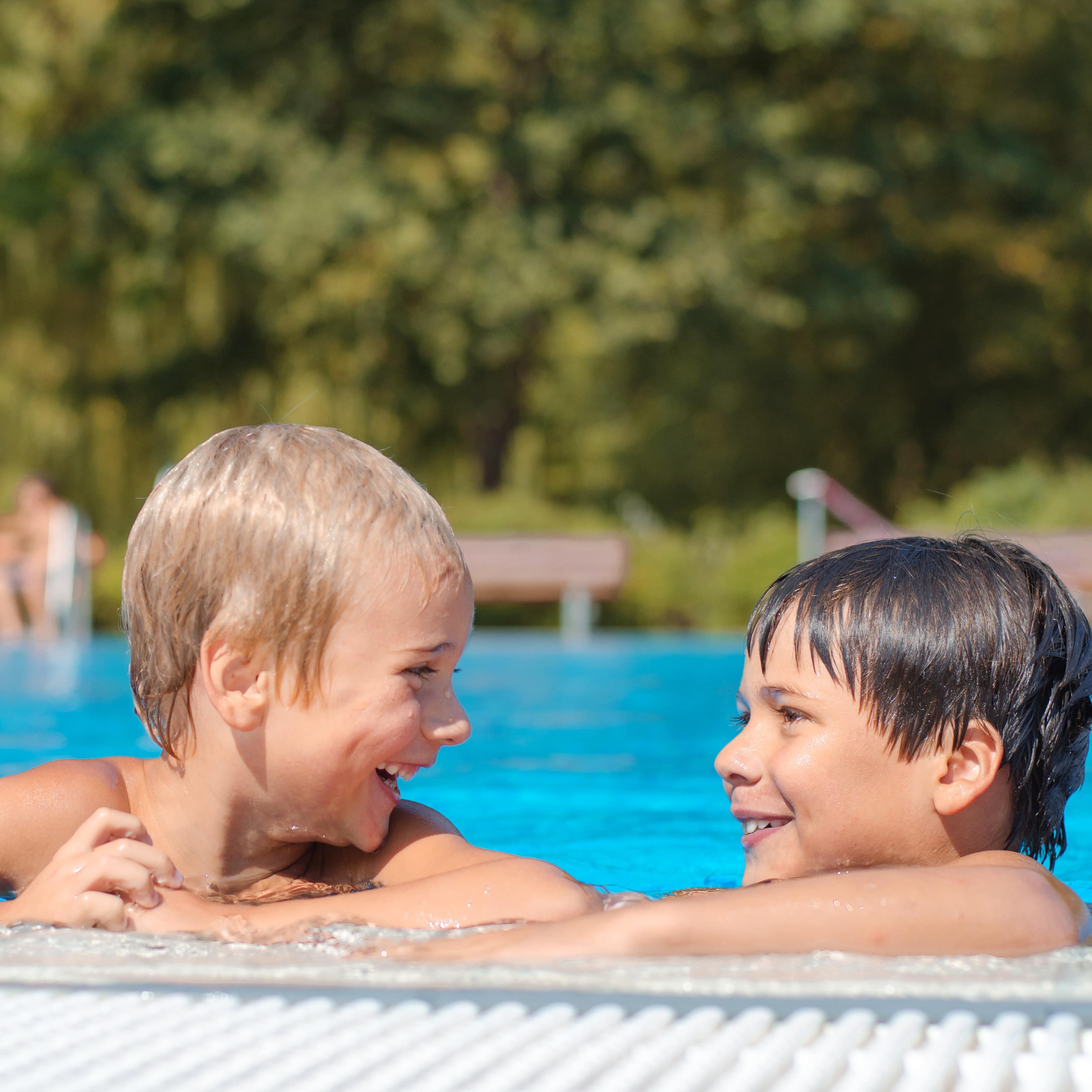 2 Jungen am Beckenrand im Freibad unterhalten sich.