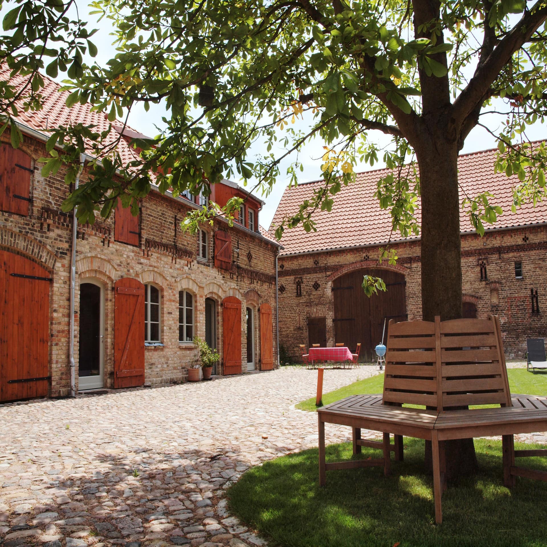 Ein gepflegter Hof mit einer Bank um einen Baum.