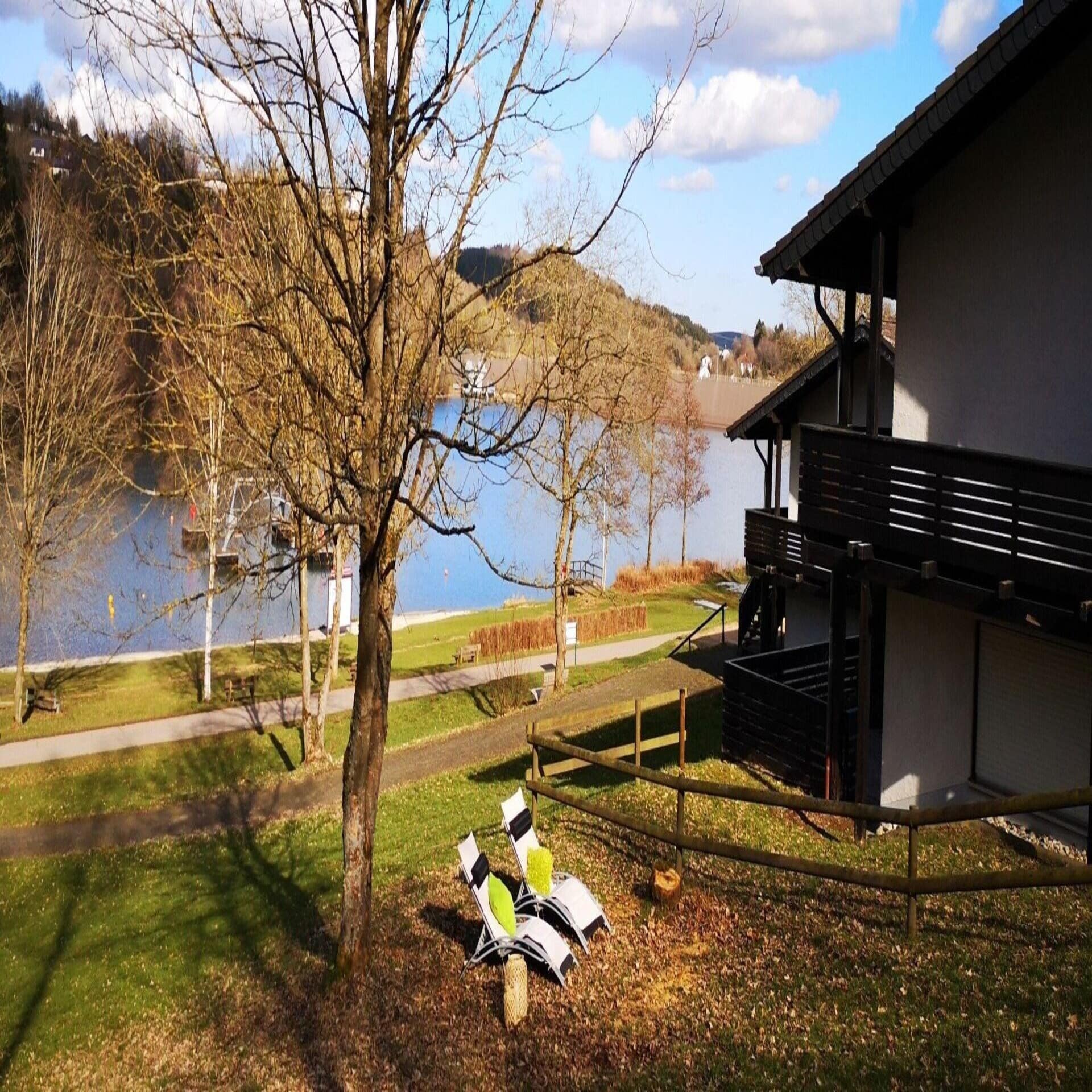 Haus mit Garten direkt am See, daneben Liegestühle.