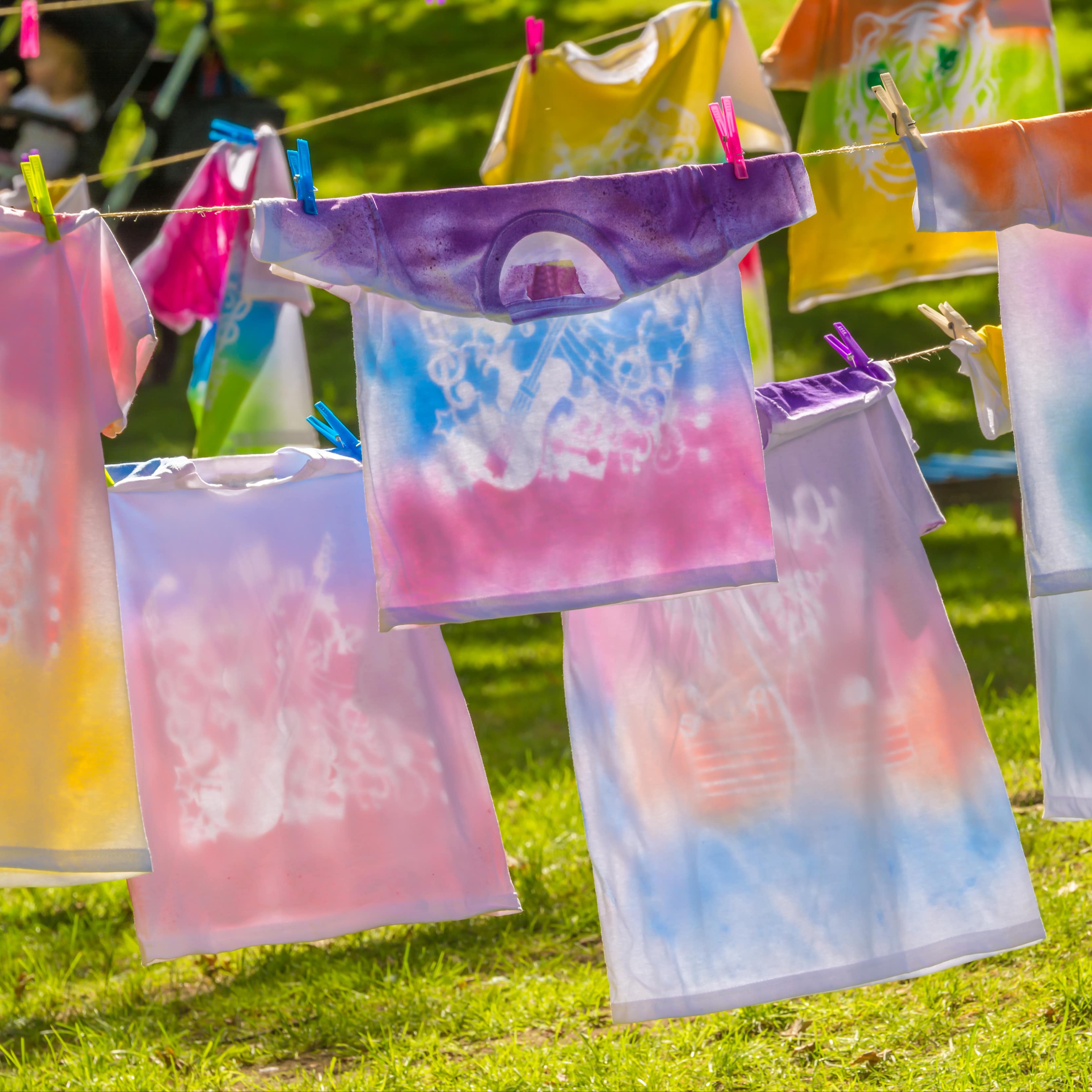 Bunt gefärbte T-Shirts hängen auf einer Leine zum Trocknen aus.
