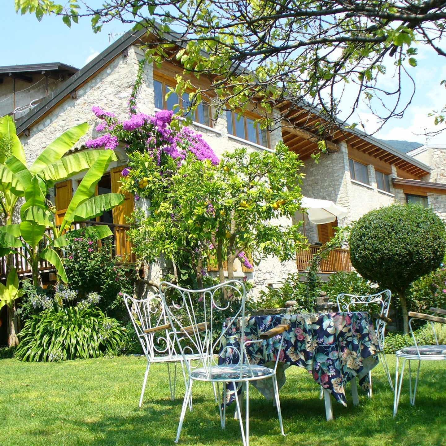 Garten mit Tisch und Stühlen und Blick auf ein Ferienhaus am Gardasee 