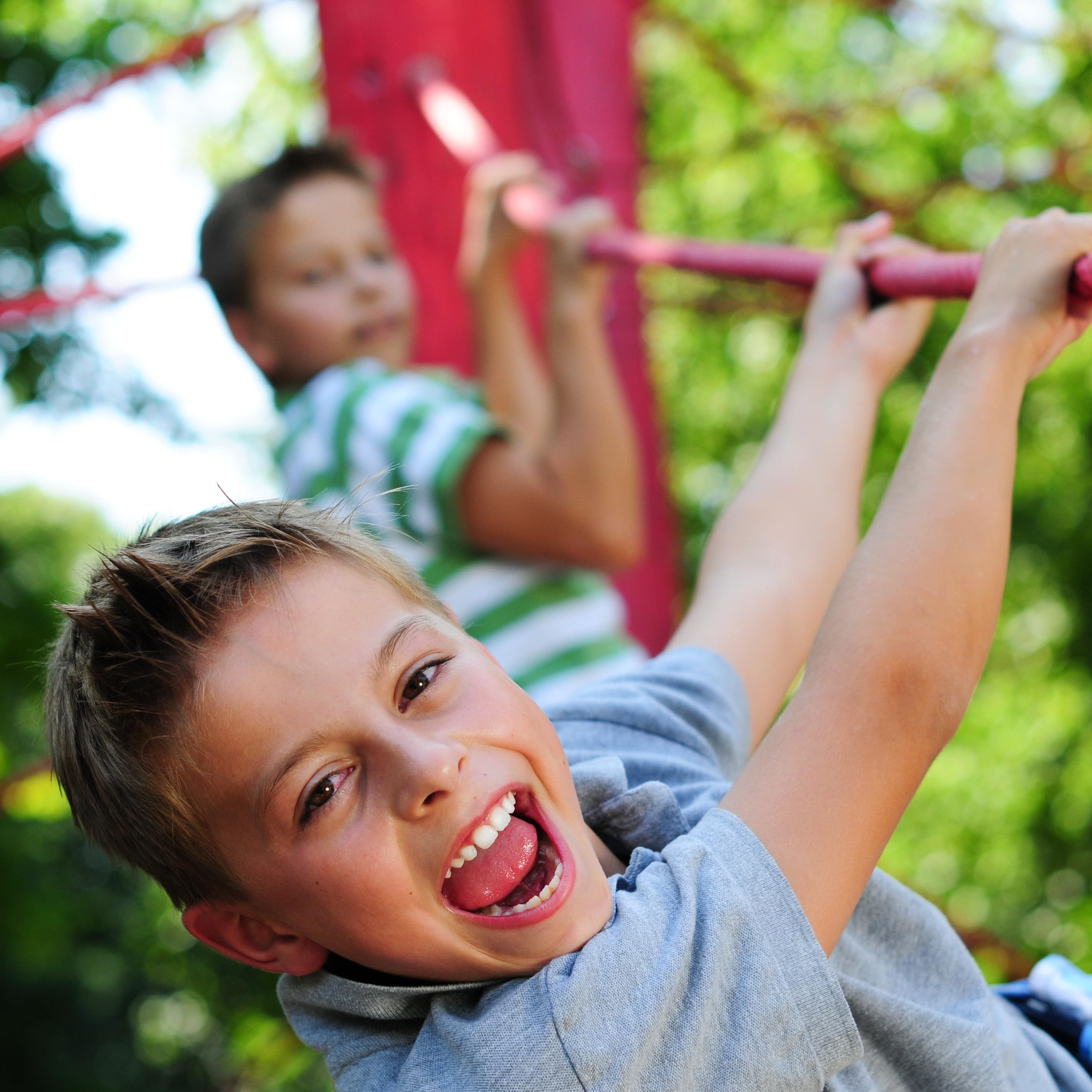  Nahaufnahme: 2 Jungen klettern auf einem Spielplatz.