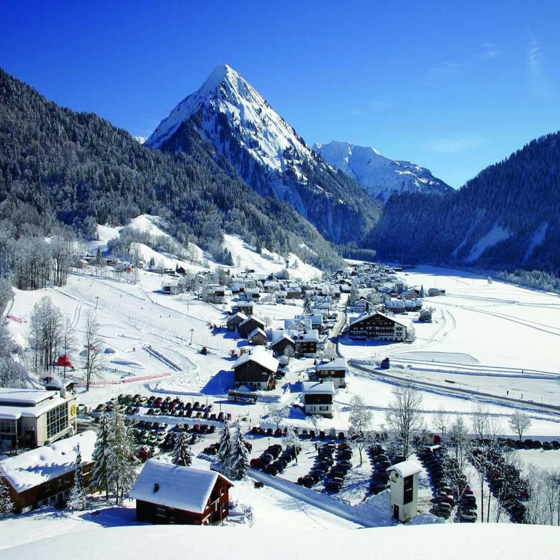 Ein verschneiter Ort im Kleinwalsertal bei Sonnenschein.