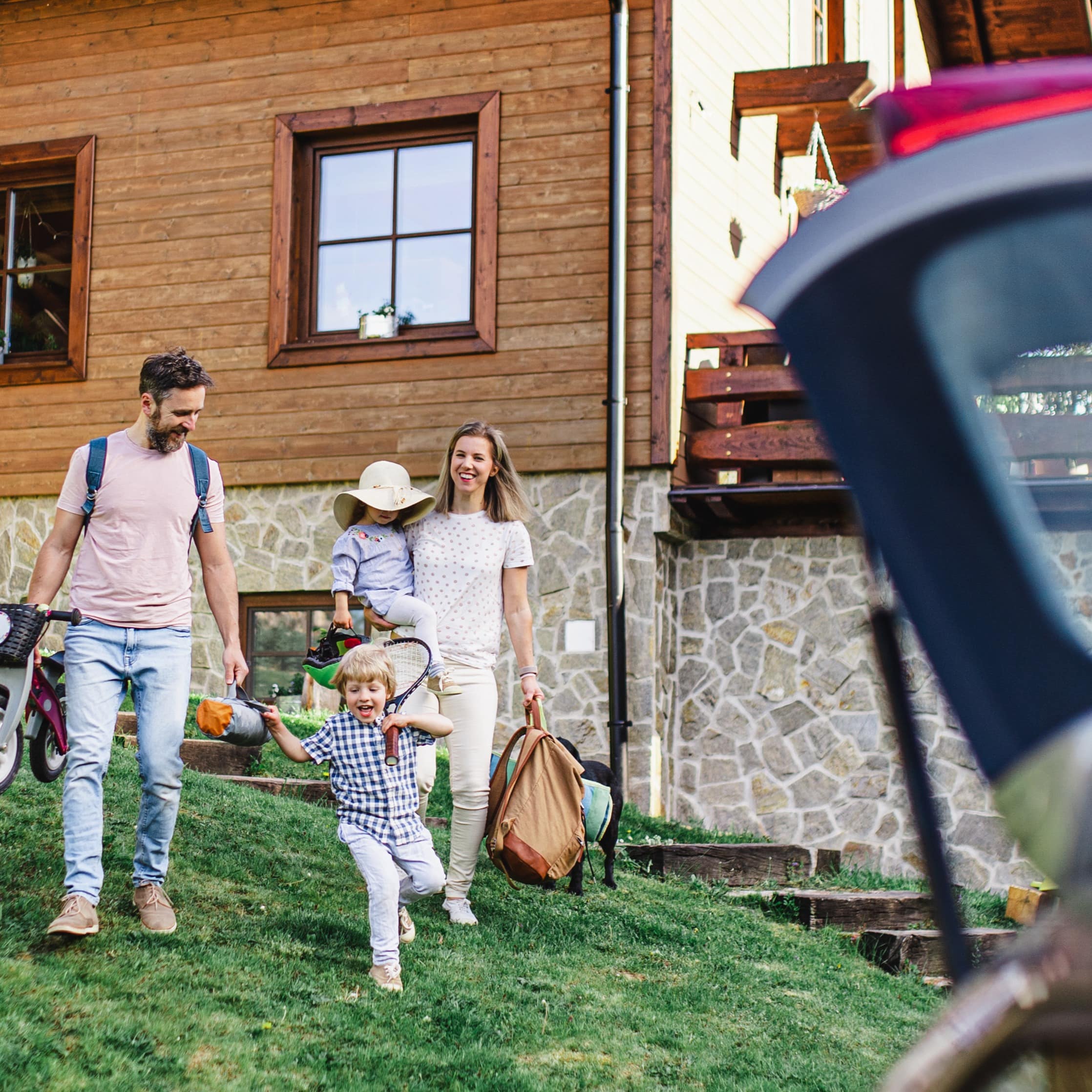 Familie mit 2 Kindern vor einem Hauseingang auf dem Weg zum Auto.