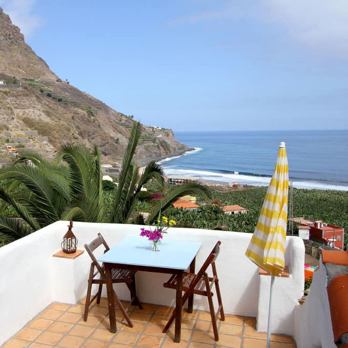 Ferienwohnung auf La Gomera mit großem Balkon, darauf Tisch und Stühle, mit Blick auf die Felsküste und über den Atlantik