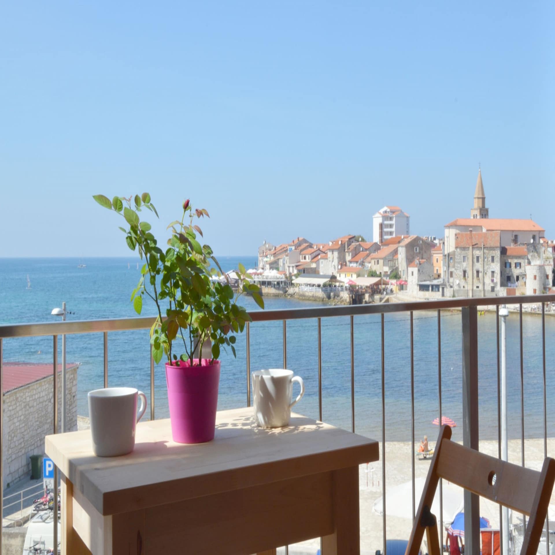 Balkon mit kleinem Tisch, 2 Kaffeetassen und 1 Pflanze sowie Blick auf das Meer und Umag.