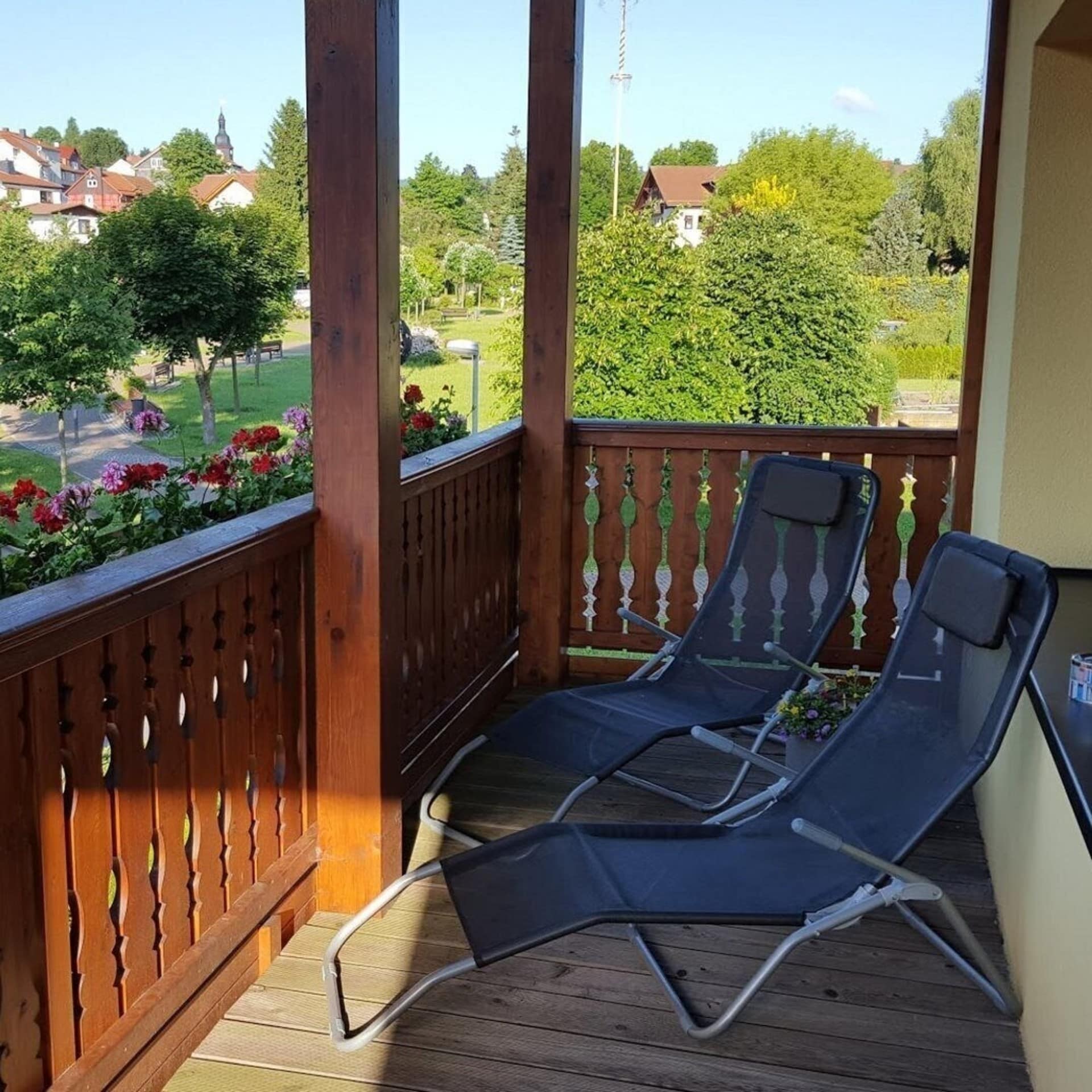 Balkon mit Liegestühlen und Blumen sowie Blick auf die Umgebung. 