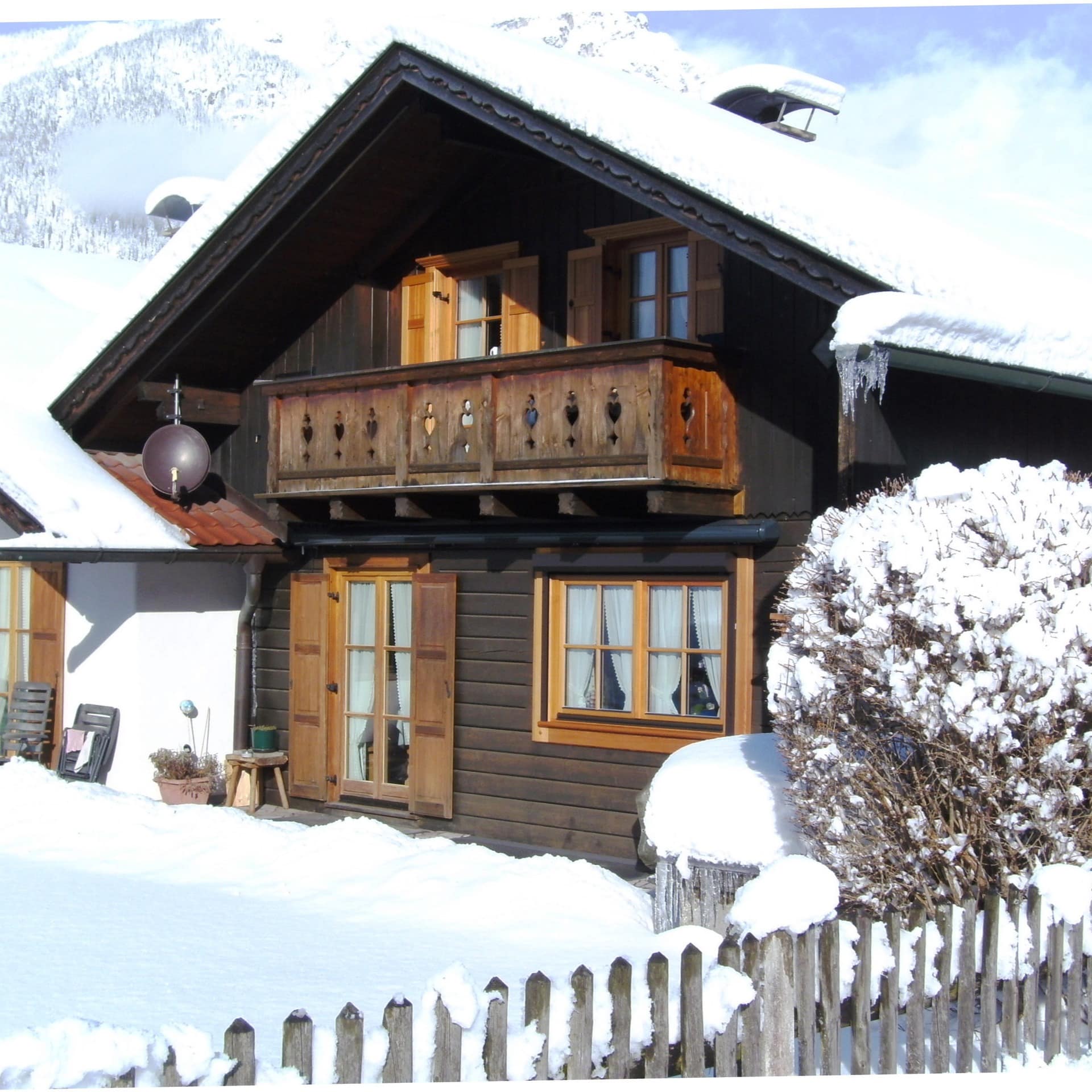 Ein kleines verschneites Holzhaus mit Ferienwohnung in Grainau 