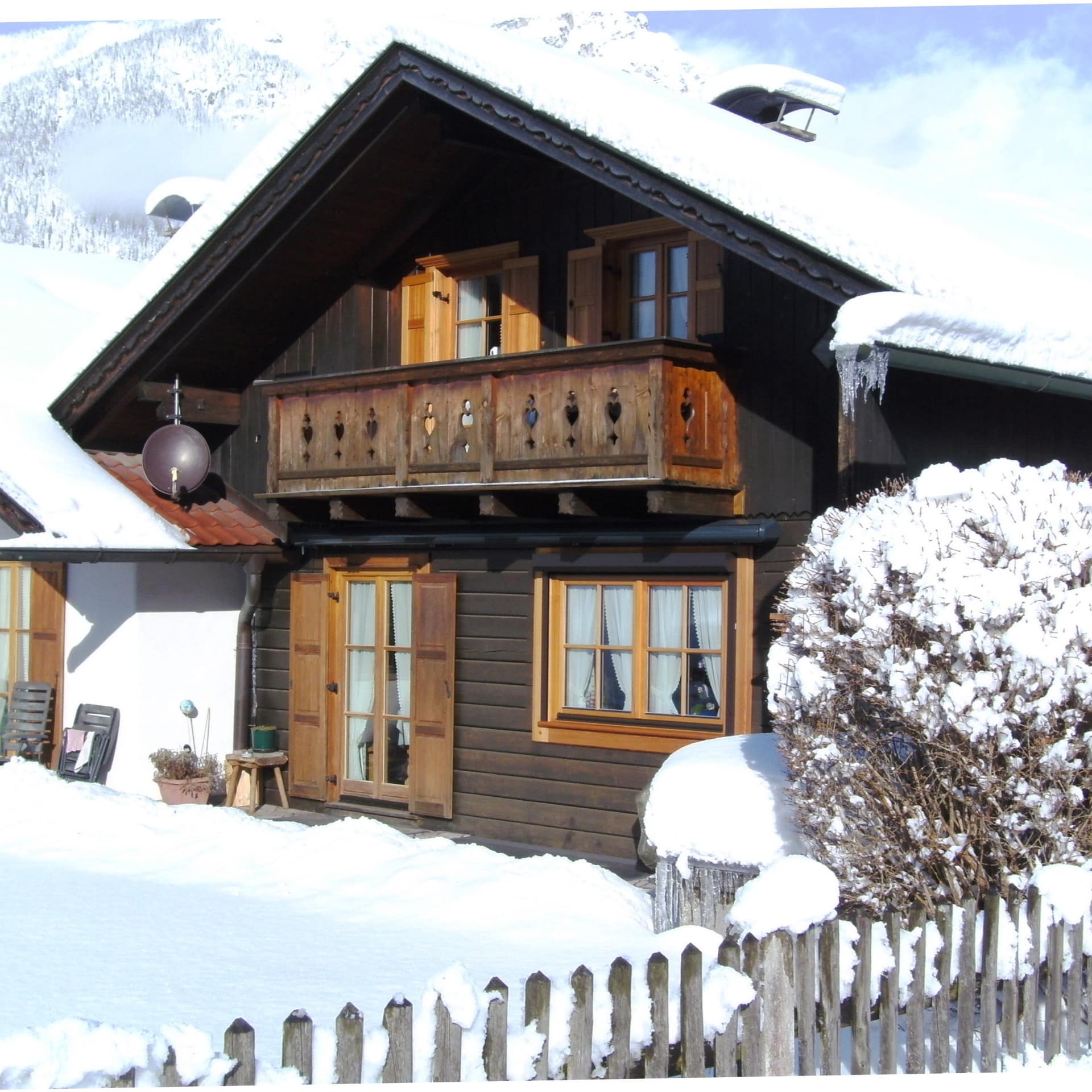 Ein kleines verschneites Holzhaus mit Ferienwohnung in Grainau