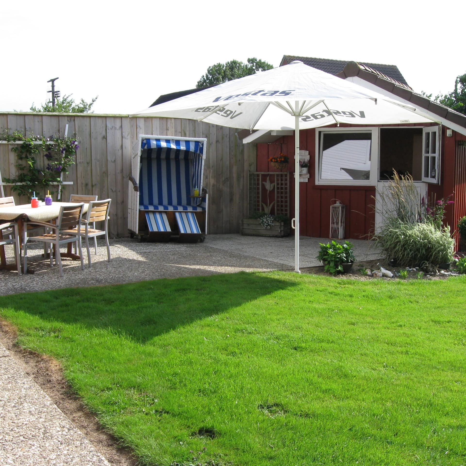 Garten mit Sitzgelegenheiten, Strandkorb und Sonnenschirm eines Ferienhauses in Nordstrand