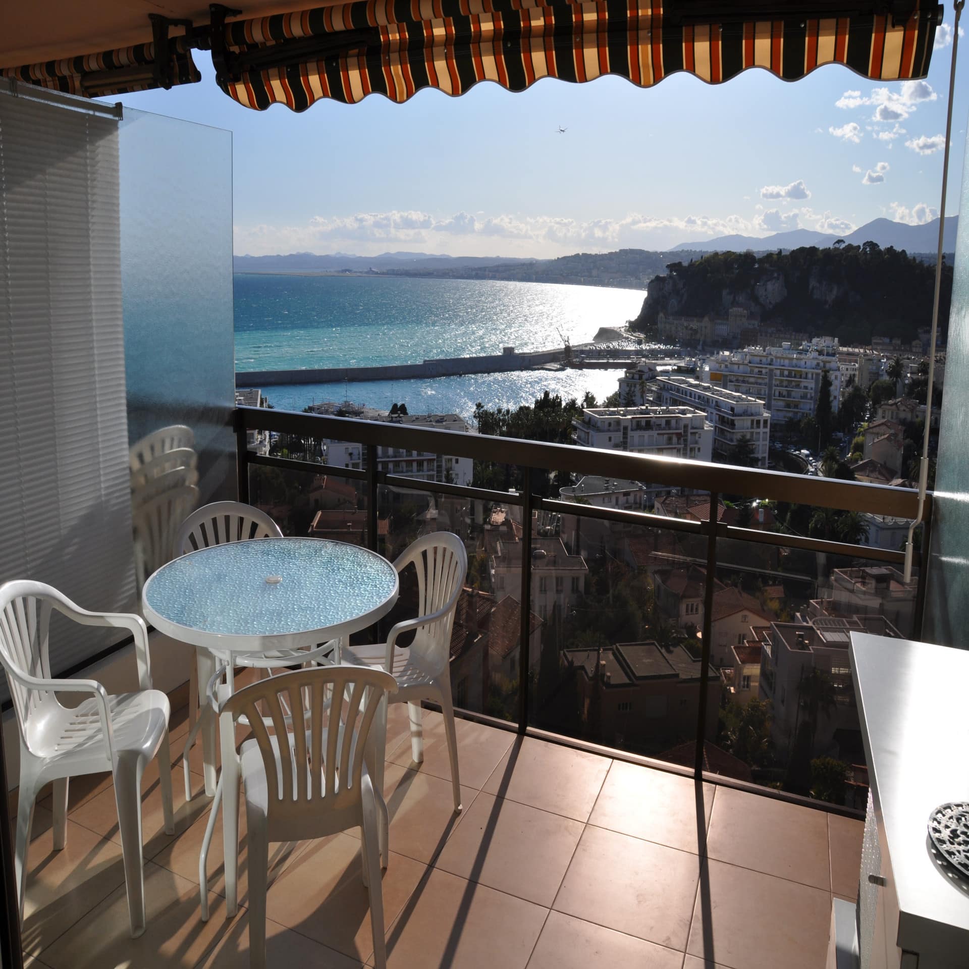 Balkon mit Tisch und 4 Stühlen und Blick auf das sonnige Nizza.