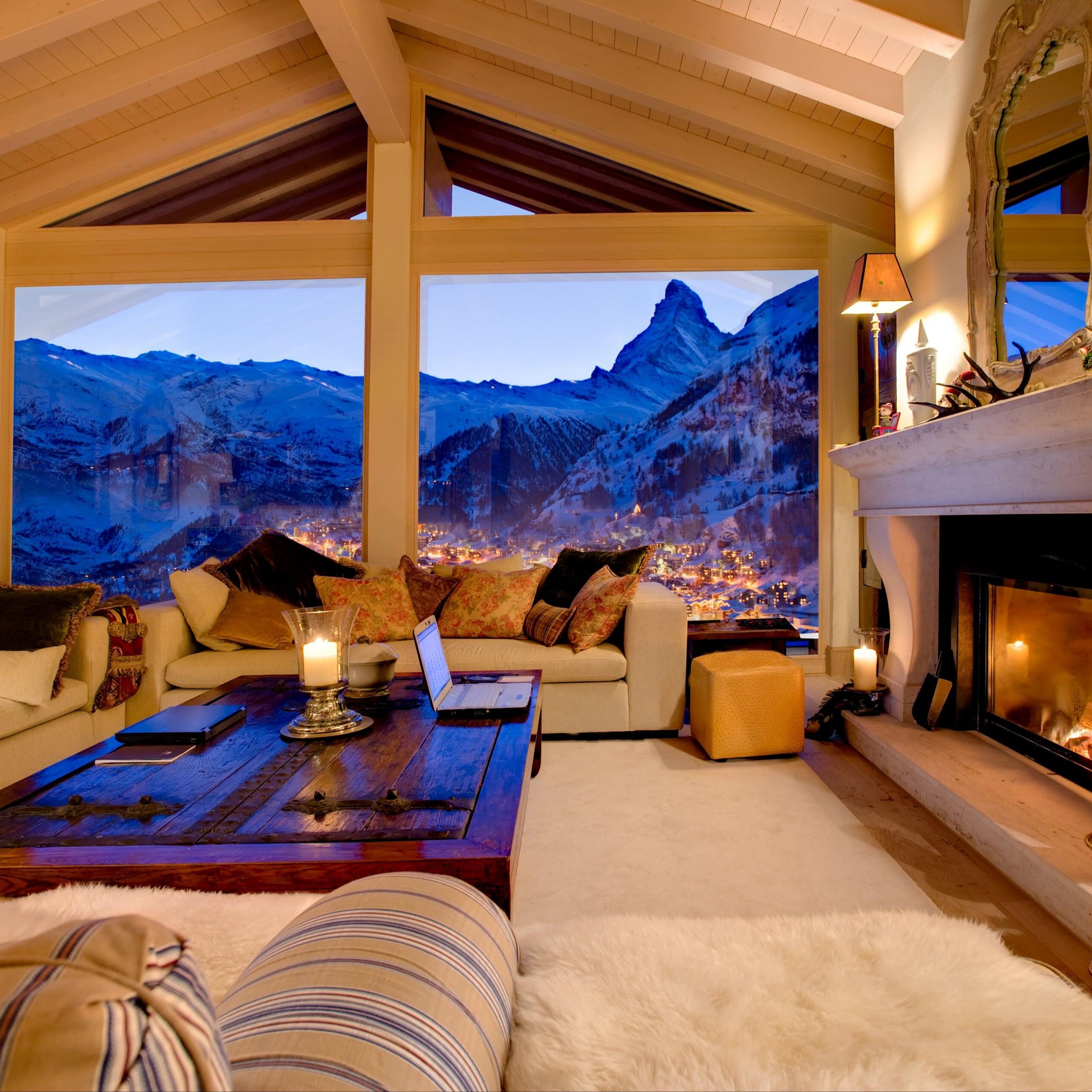 Ferienhaus in der Schweiz mit großem Wohnraum, offenem Kamin, hellen Sofas und Blick aufs Bergpanorama
