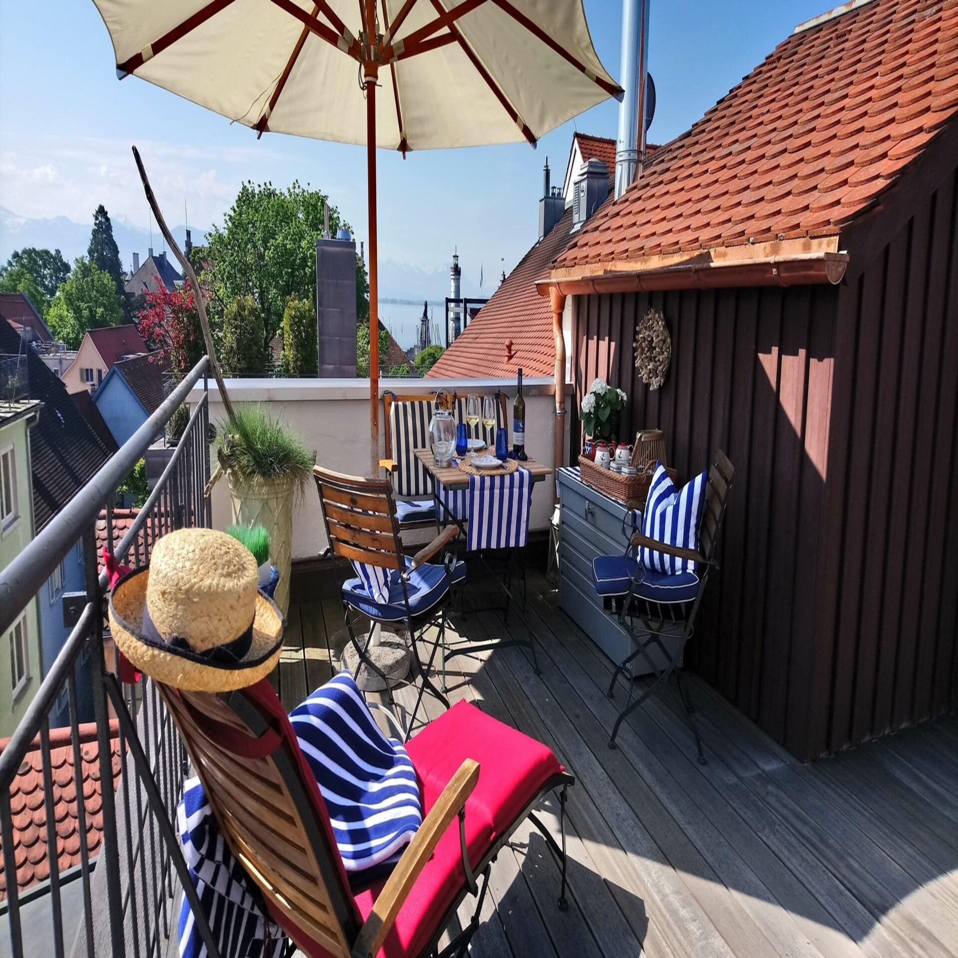 Dachterrasse mit Sitzgelegenheiten, Sonnenliege und Sonnenschirm und Blick auf den Bodensee.