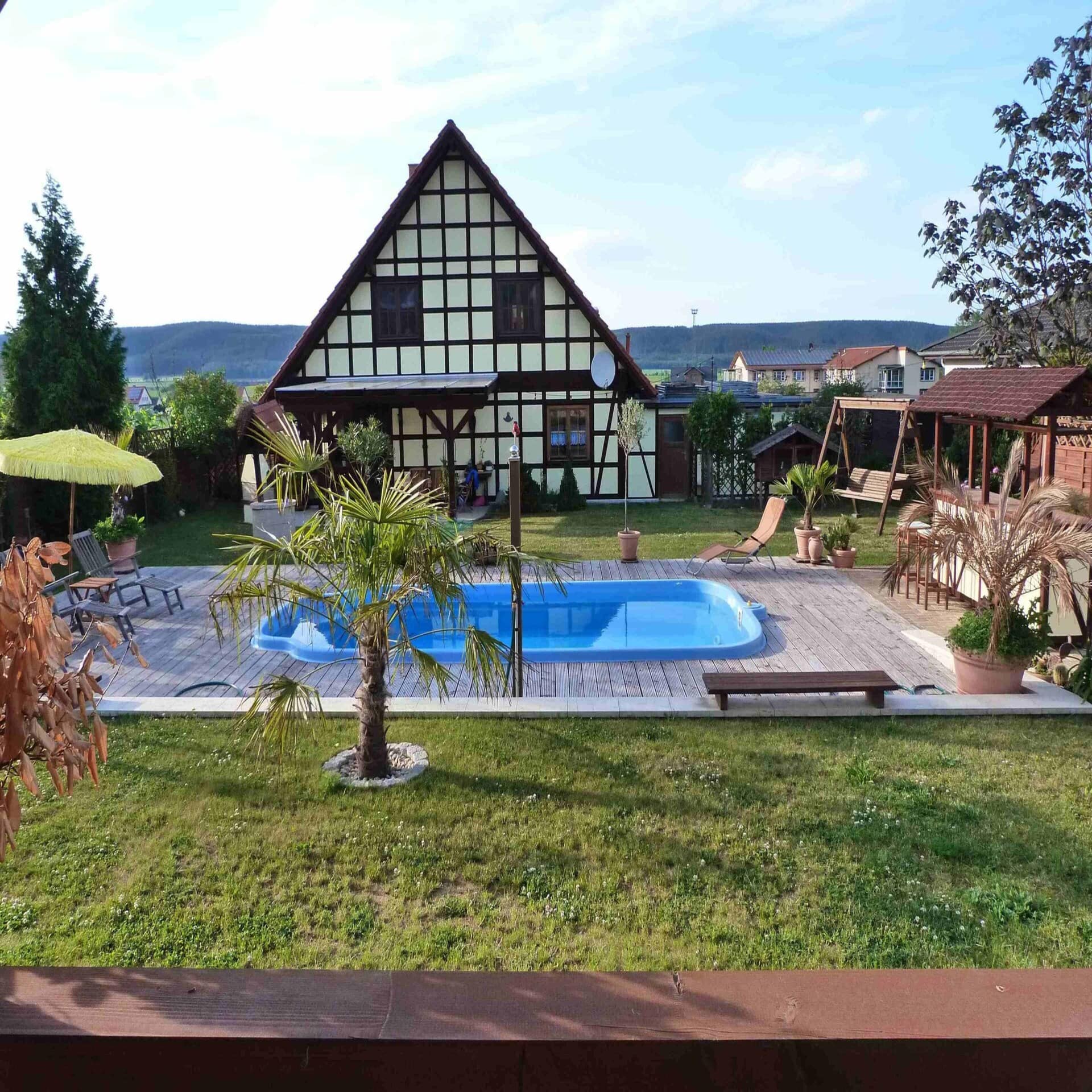 Fachwerkhaus mit mediterraner Pollandschaft im Garten.